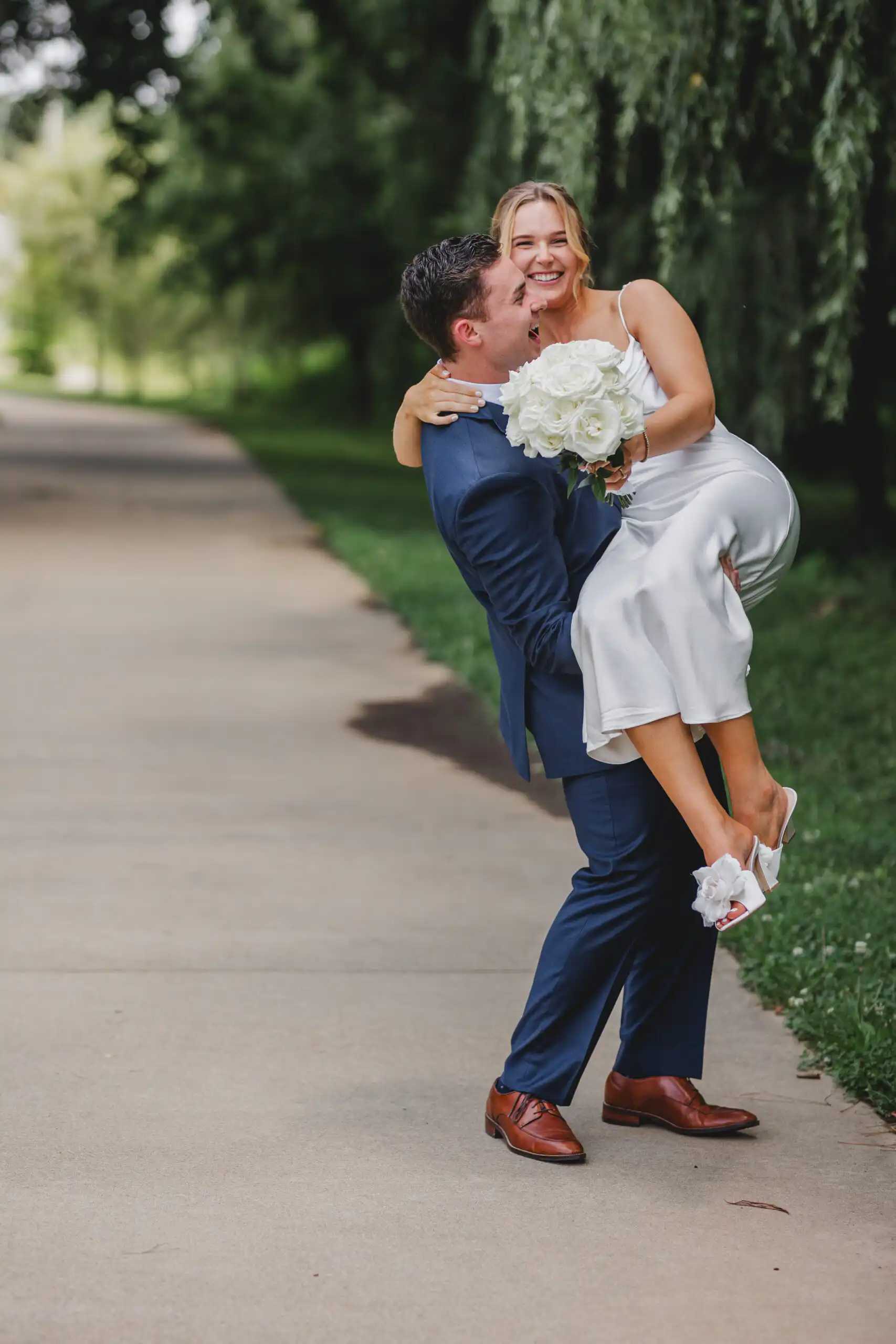 Wedding Formals: him lifting her off the path, both laughing, after their courthouse wedding at Brookhaven City Hall in Brookhaven, GA