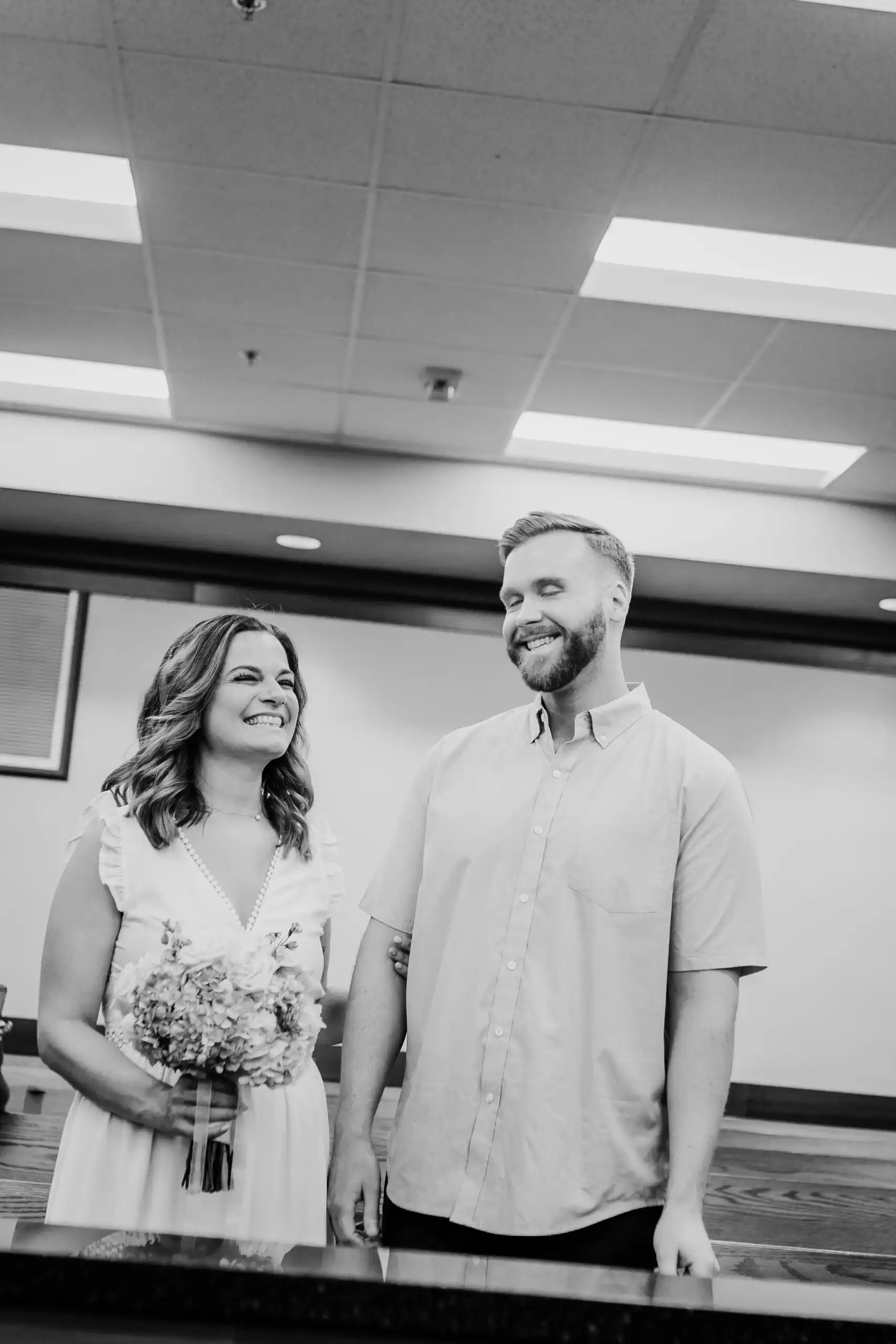 Wedding Formals: laughing at the counter, in black and white, at their courthouse wedding at the Cobb County Courthouse in Marietta, GA
