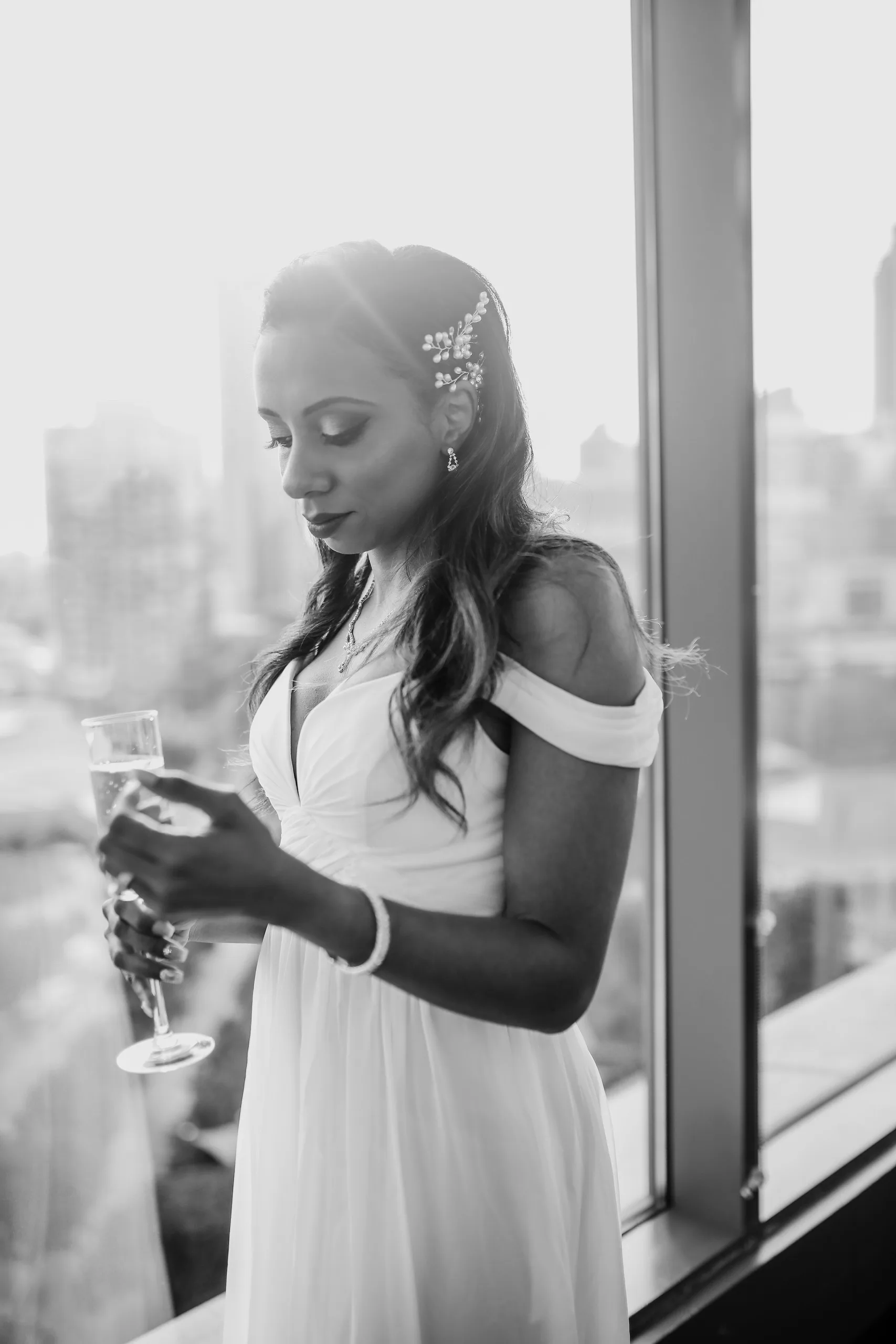 Bridal Portraits: the bride at the window with a glass of champagne, in black and white, at their elopement at Ventanas in Atlanta, GA