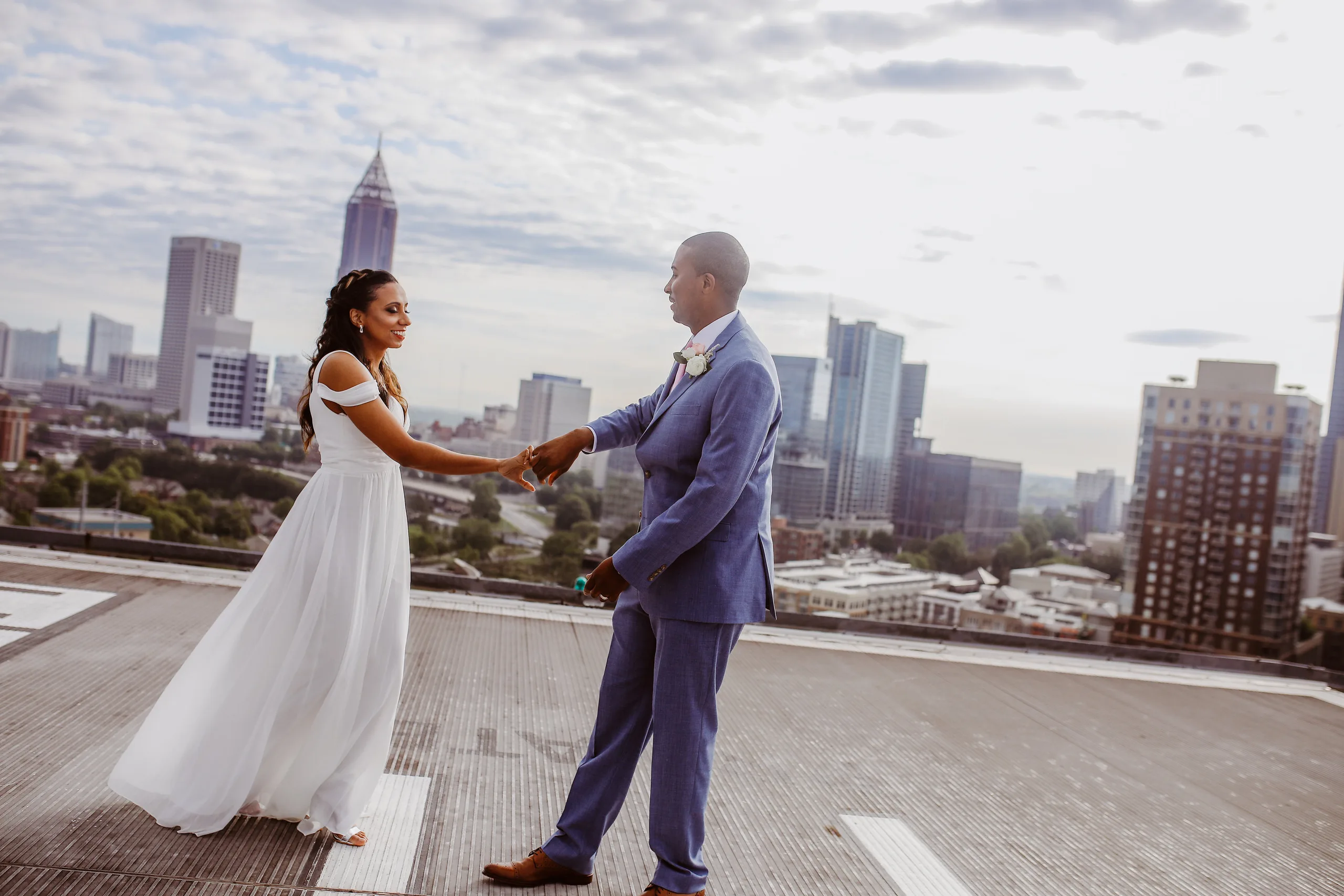 Wedding Formals: holding hands on the helipad with the skyline behind them, at their elopement at Ventanas in Atlanta, GA