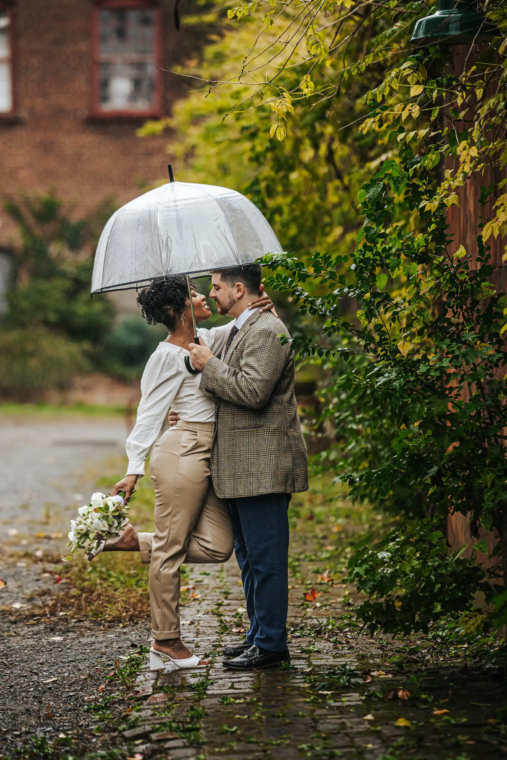 Wedding Formals: the two of them under a clear umbrella in the rain, at their wedding at the Goat Farm in Atlanta, GA