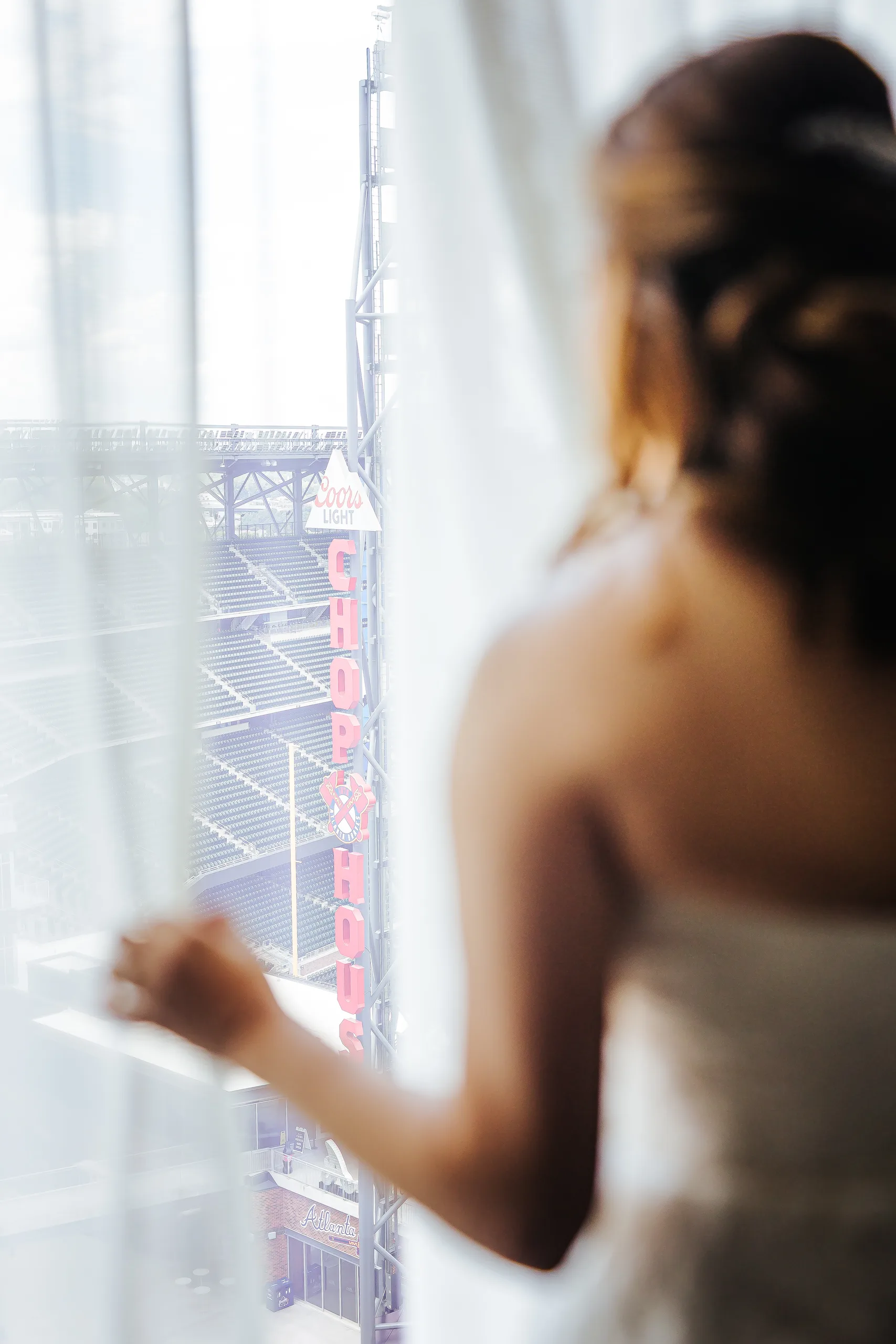 Getting Ready: the bride looking out at the ballpark from her room before their wedding at the Omni Hotel at The Battery in Atlanta, GA