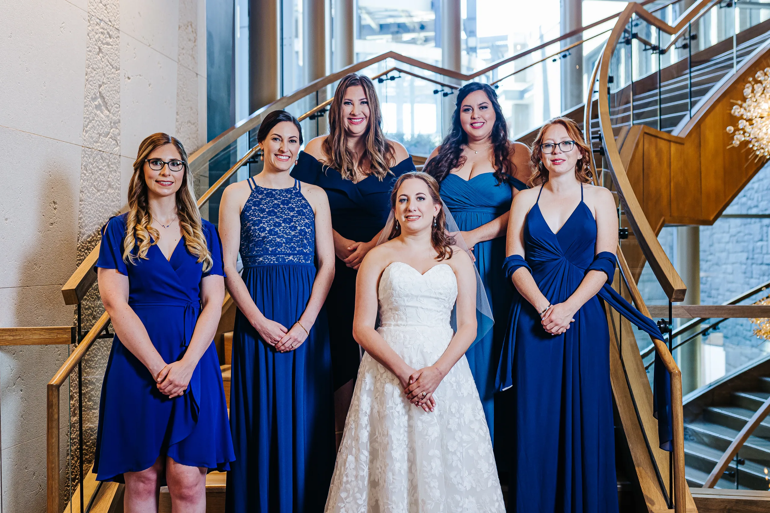 Wedding Party: the bride with her bridesmaids in navy and blue on the staircase at their wedding at the Omni Hotel at The Battery in Atlanta, GA