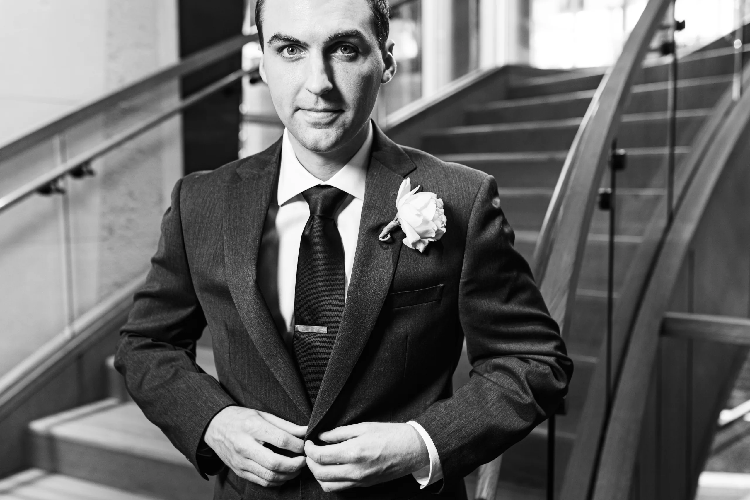 Wedding Formals: the groom fixing his jacket, in black and white before their wedding at the Omni Hotel at The Battery in Atlanta, GA