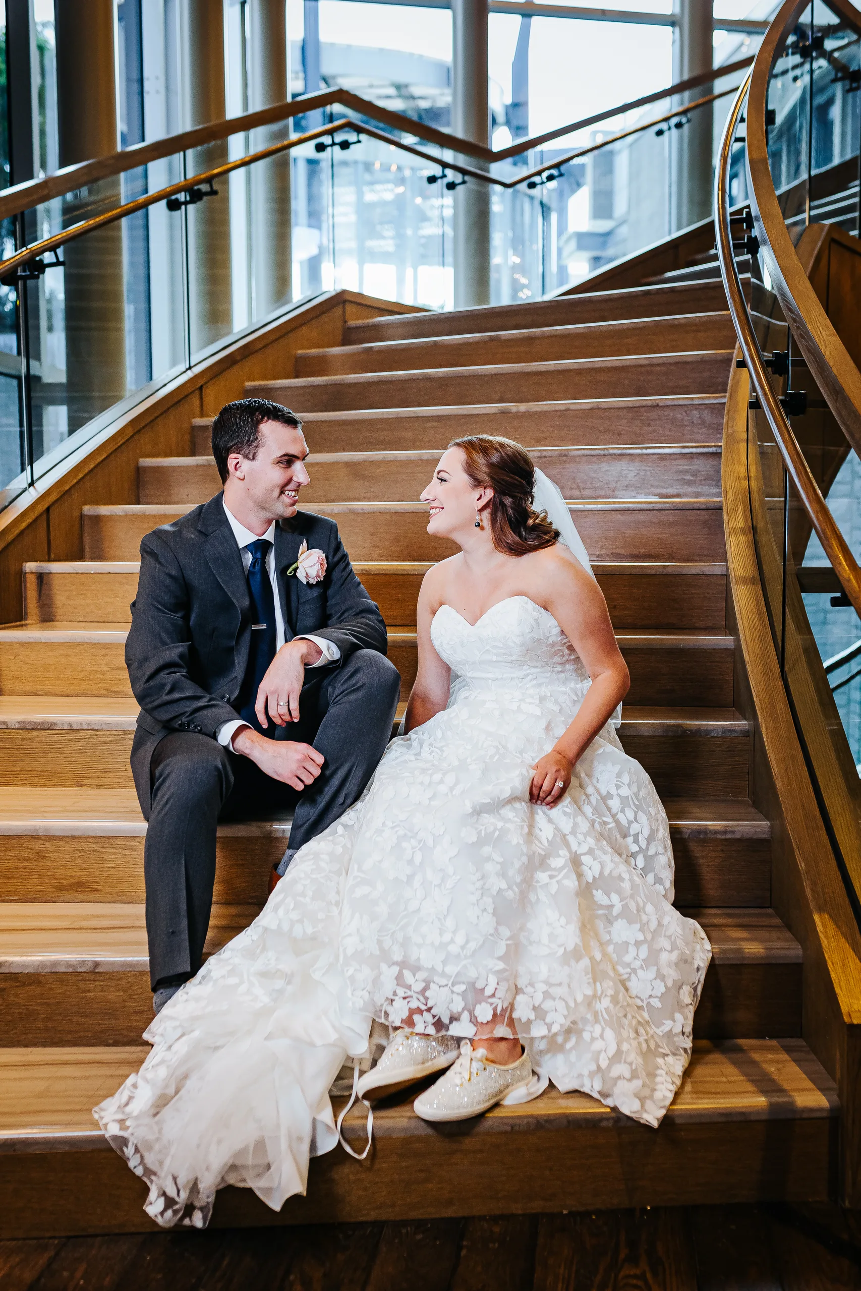 Wedding Formals: sitting together on the staircase with her Keds showing at their wedding at the Omni Hotel at The Battery in Atlanta, GA