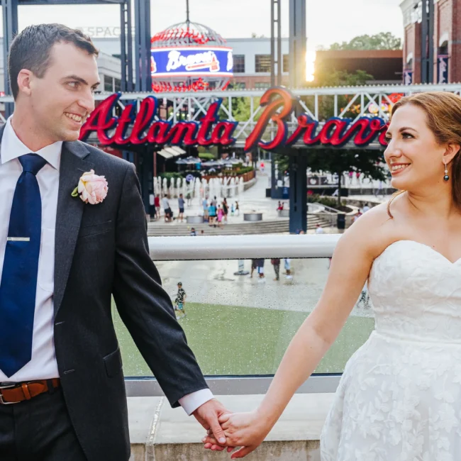 Wedding Formals: holding hands in front of the Atlanta Braves sign at their wedding at the Omni Hotel at The Battery in Atlanta, GA
