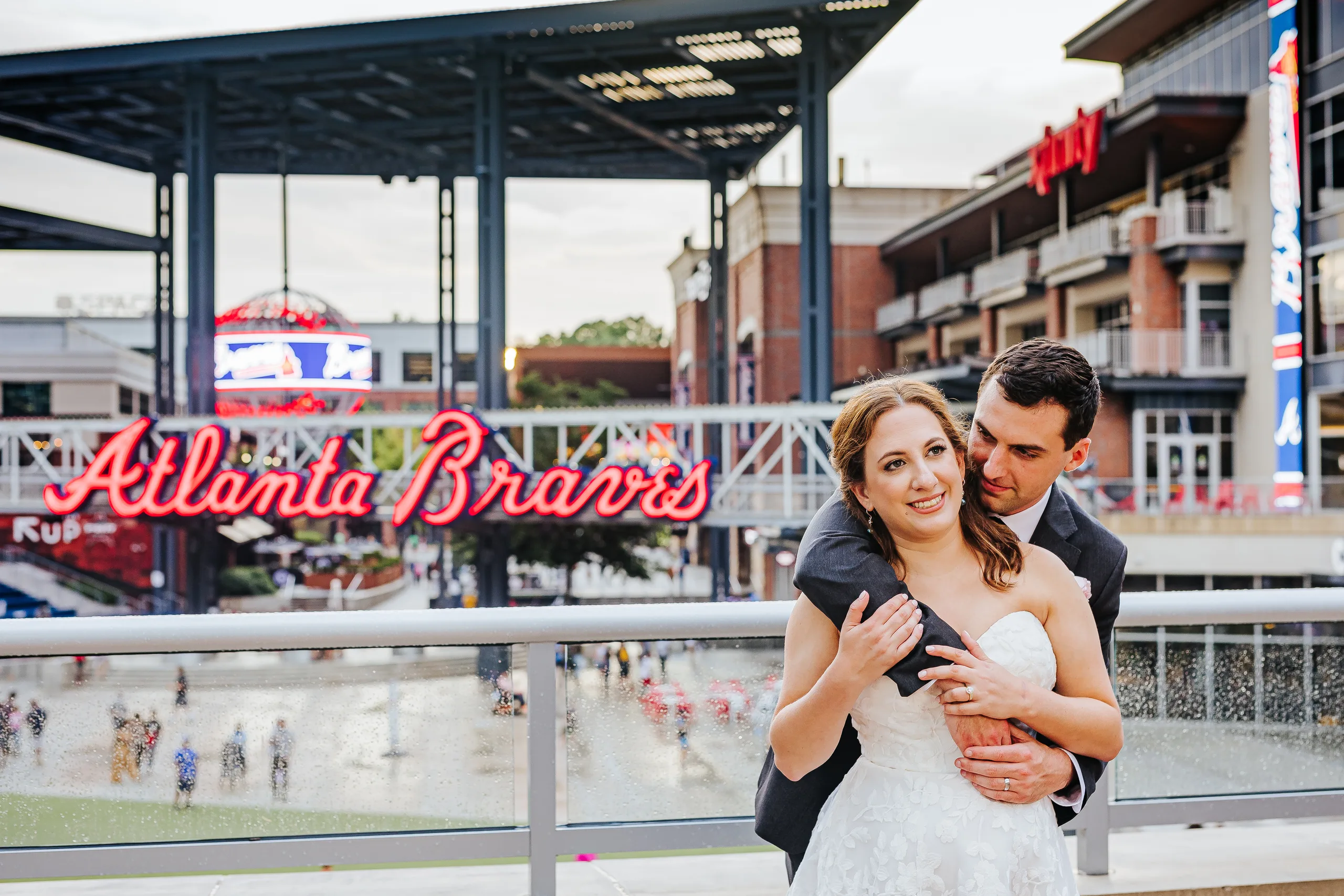 Wedding Formals: a hug from behind under the Atlanta Braves sign at their wedding at the Omni Hotel at The Battery in Atlanta, GA