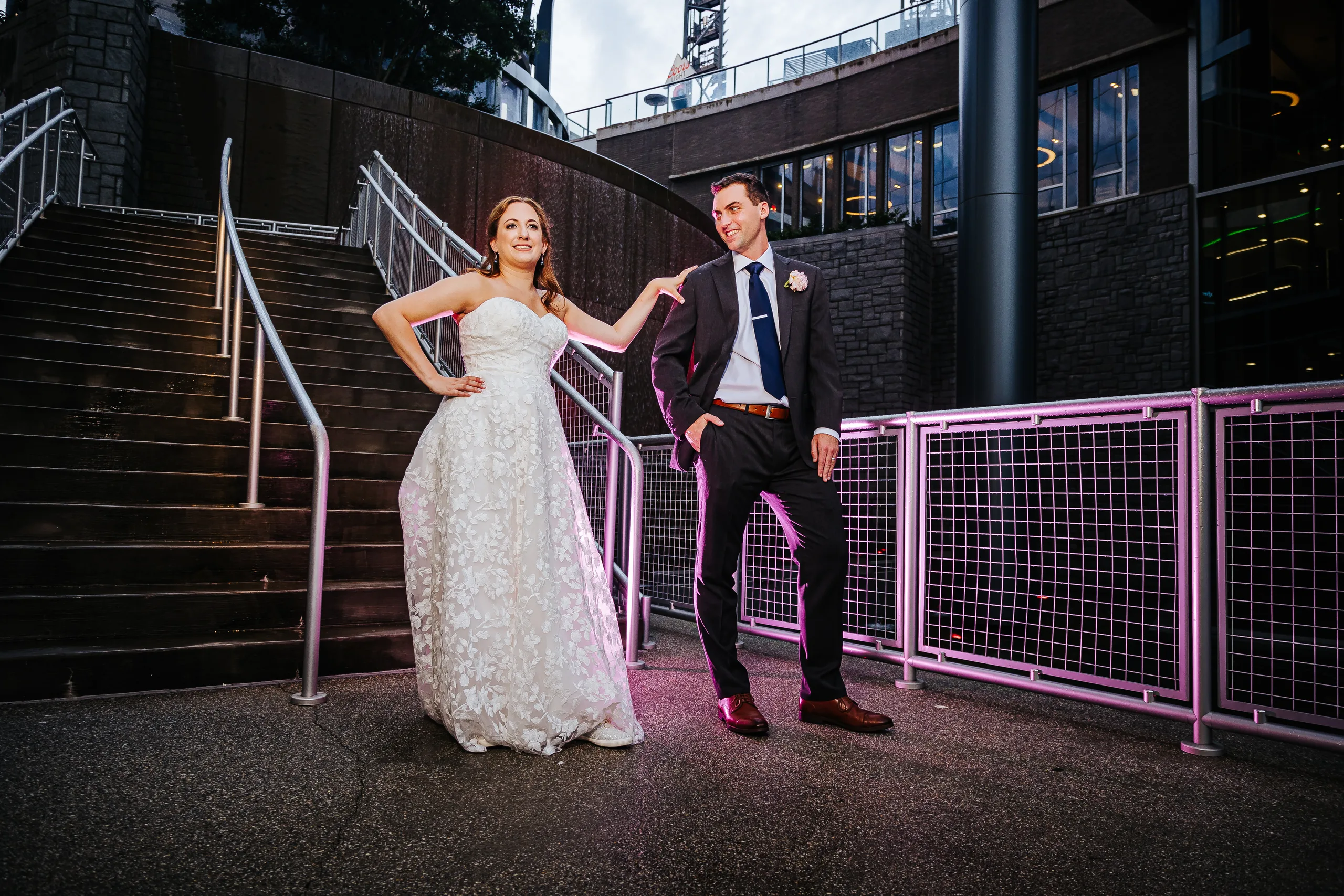 Wedding Formals: a playful pose by the stairs with pink railings at their wedding at the Omni Hotel at The Battery in Atlanta, GA