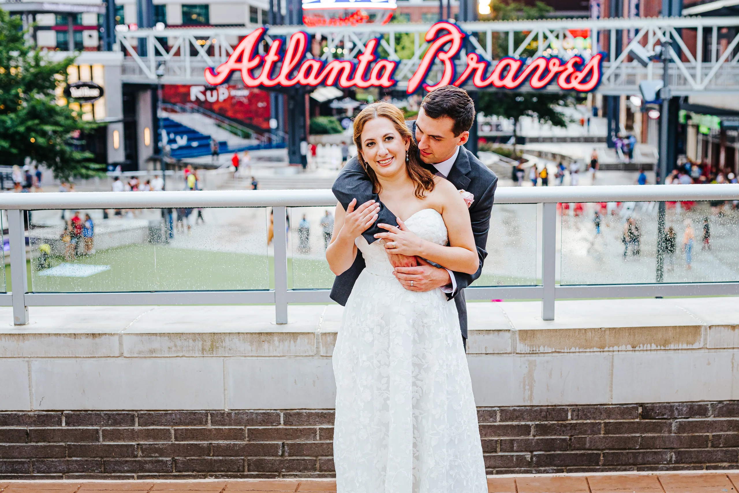 Wedding Formals: smiling in front of the Atlanta Braves sign at The Battery at their wedding at the Omni Hotel at The Battery in Atlanta, GA