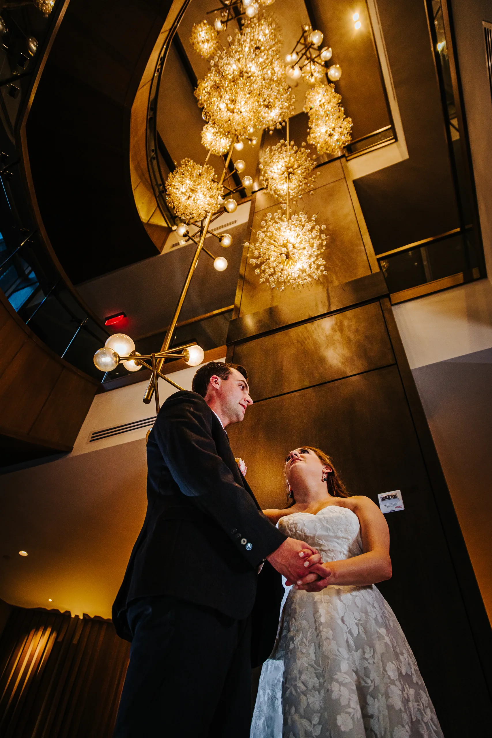 Wedding Formals: holding hands under the sparkler chandelier at their wedding at the Omni Hotel at The Battery in Atlanta, GA