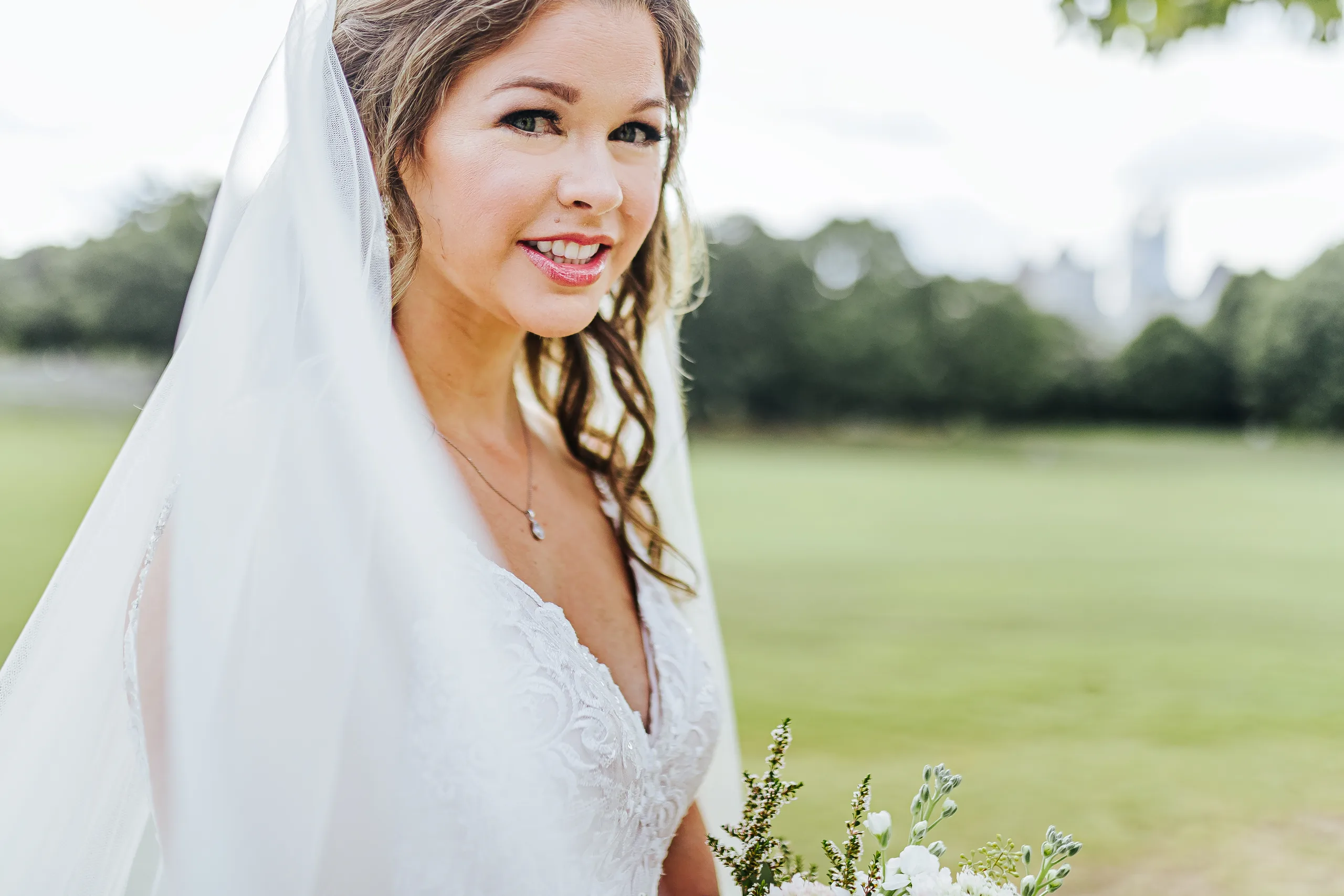 Bridal Portraits: the bride with the Midtown skyline behind her on the meadow in Piedmont Park, at their wedding at The Piedmont Room in Atlanta, GA