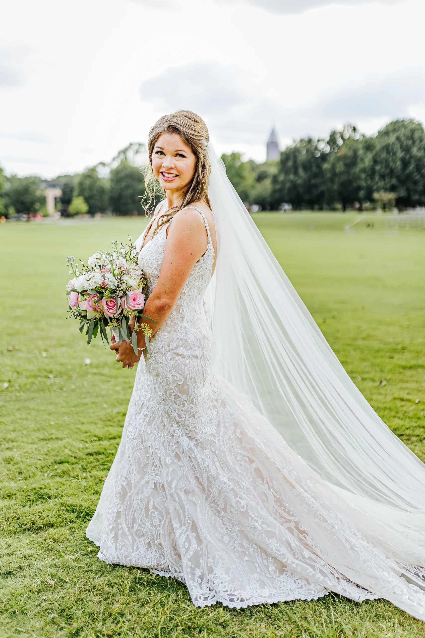 Bridal Portraits: the bride with her cathedral veil on the meadow in Piedmont Park, at their wedding at The Piedmont Room in Atlanta, GA