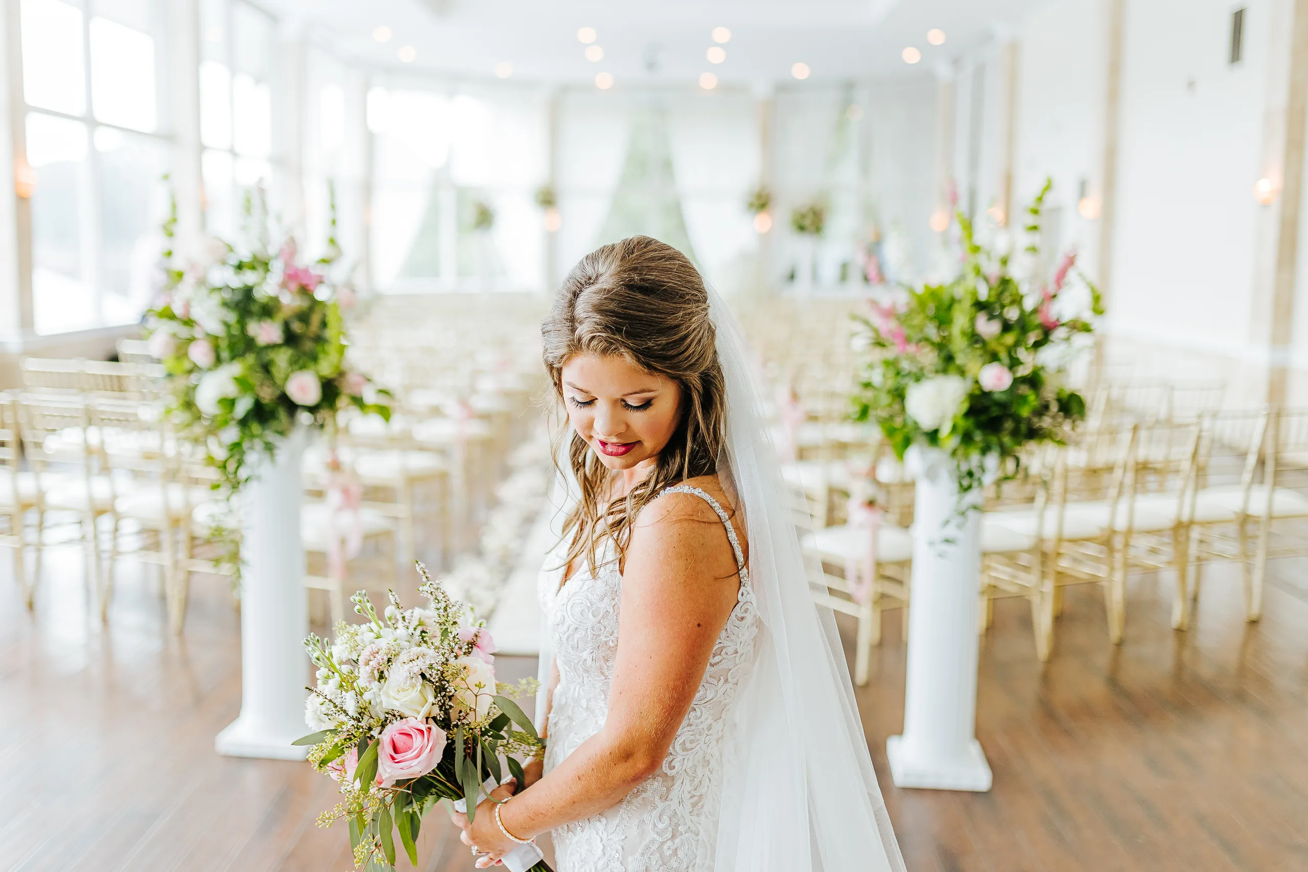 Bridal Portraits: the bride looking down at her bouquet in the ceremony room, at their wedding at The Piedmont Room in Atlanta, GA