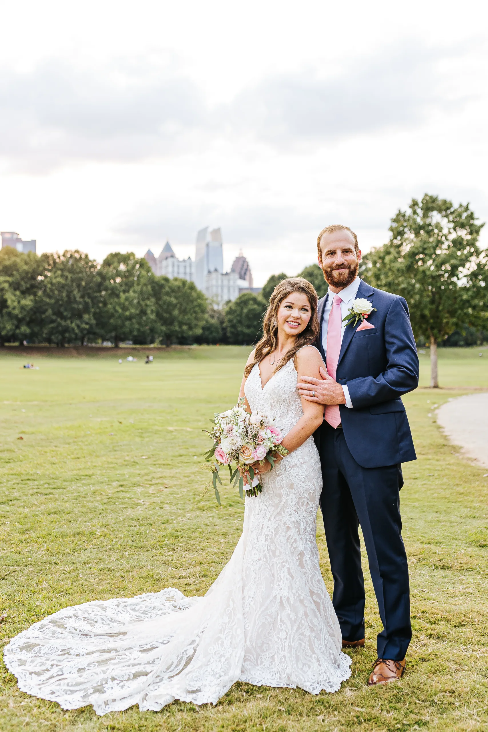 Wedding Formals: the couple with the Midtown skyline behind them on the meadow in Piedmont Park, at their wedding at The Piedmont Room in Atlanta, GA