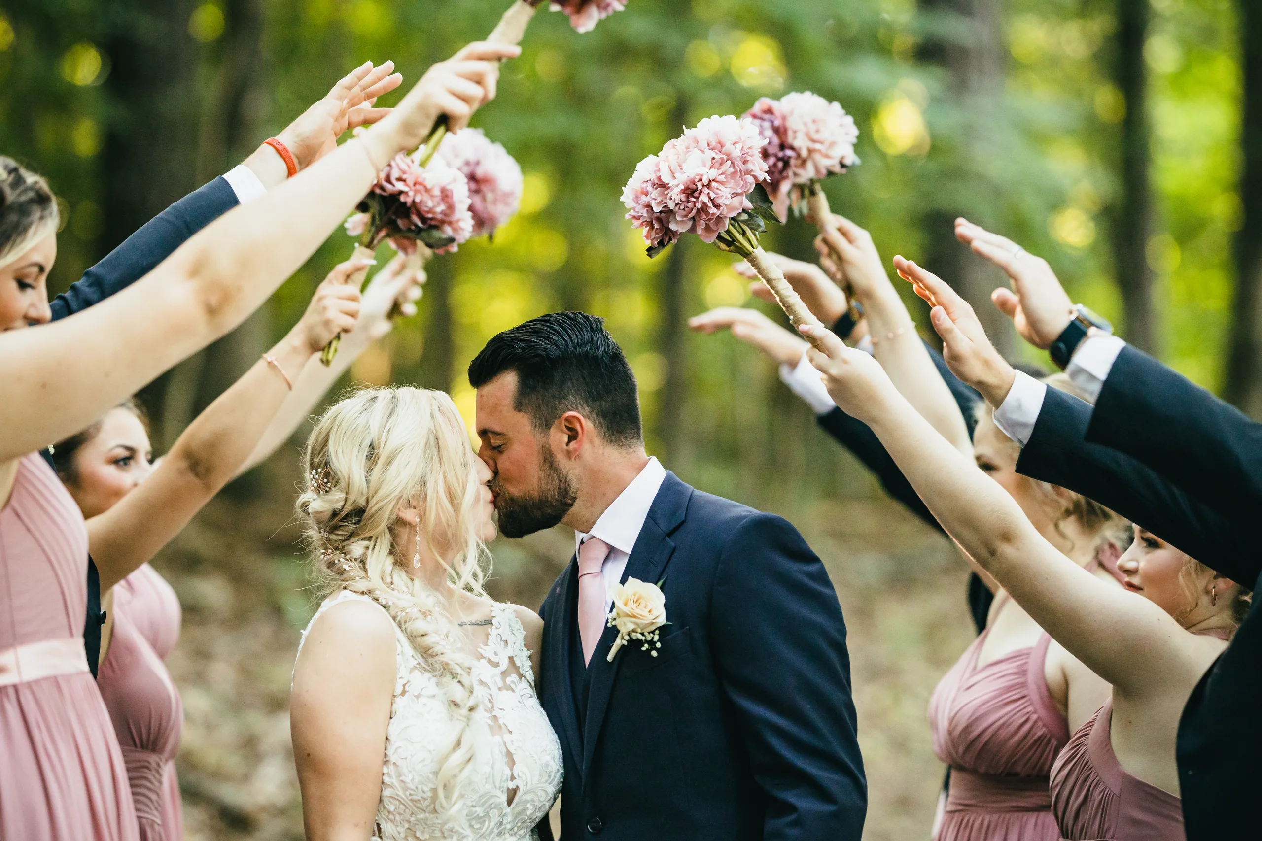 Wedding Party: a kiss under an arch of bouquets, at their wedding at Atlanta Evergreen Lakeside Resort in Stone Mountain, GA