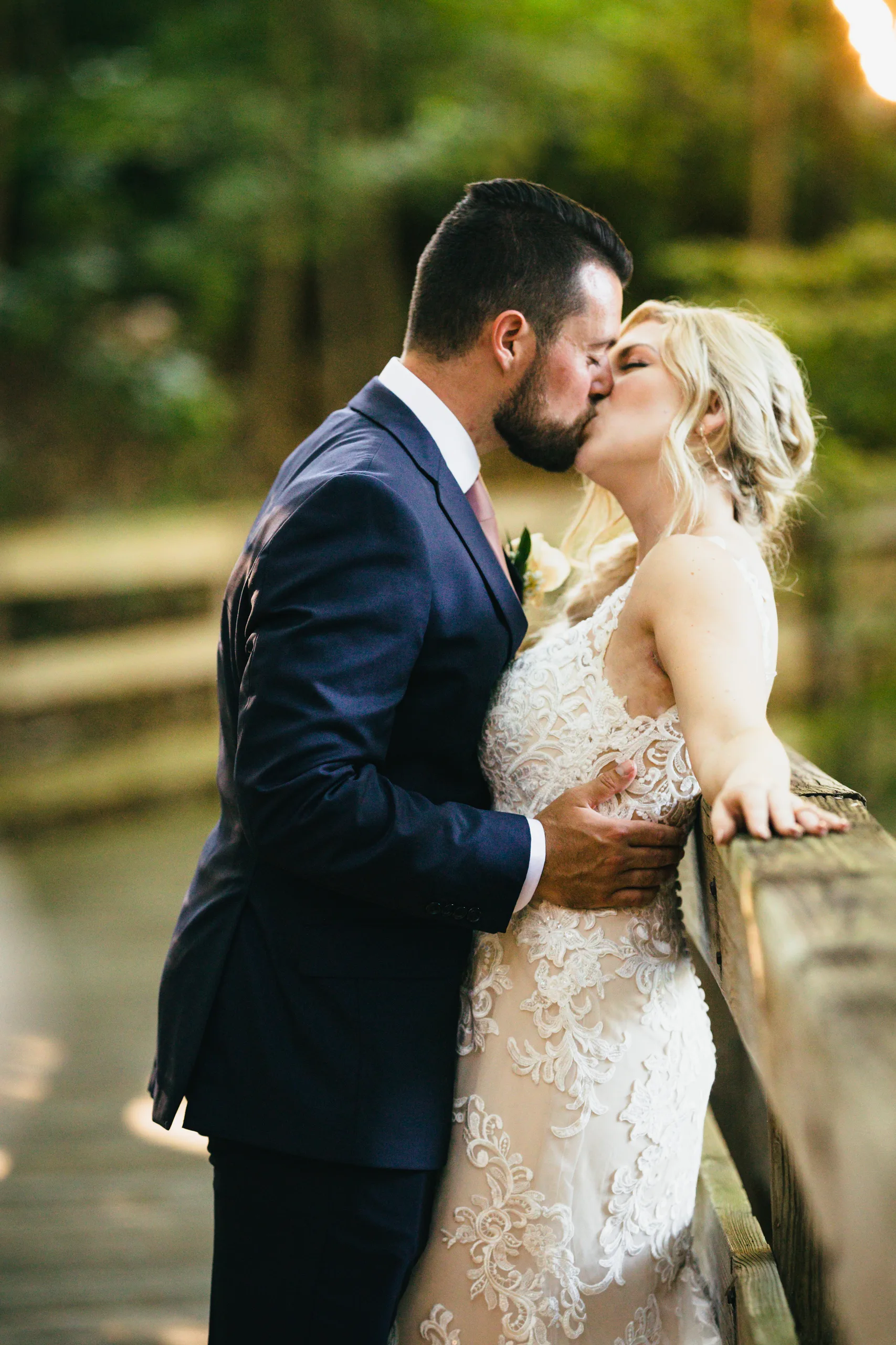 Wedding Formals: a kiss against the railing of the footbridge, at their wedding at Atlanta Evergreen Lakeside Resort in Stone Mountain, GA