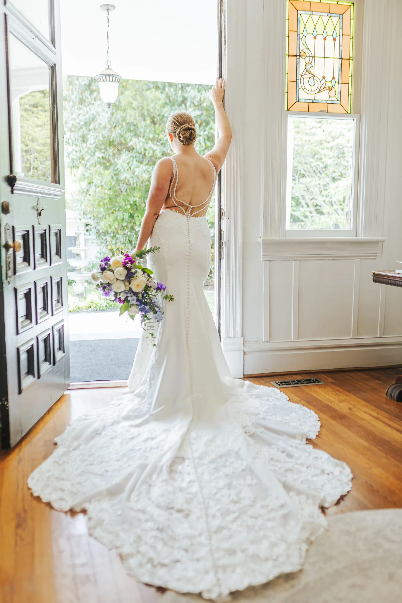 Bridal Portraits: the bride in the doorway of the mansion with her bouquet, at their wedding at The Wildflower 301 in Greensboro, GA