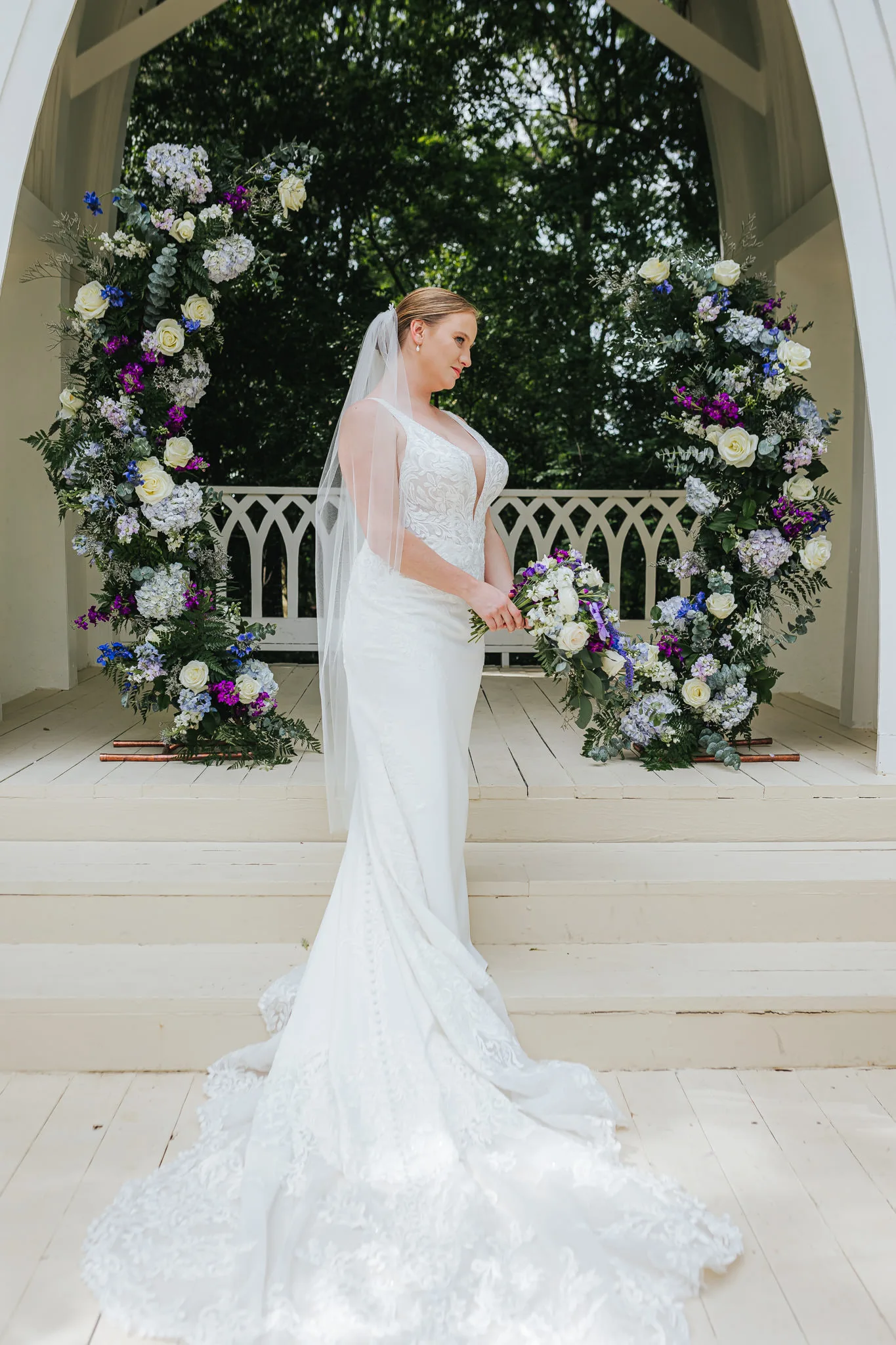 Bridal Portraits: the bride under the chapel arch with her bouquet, at their wedding at The Wildflower 301 in Greensboro, GA