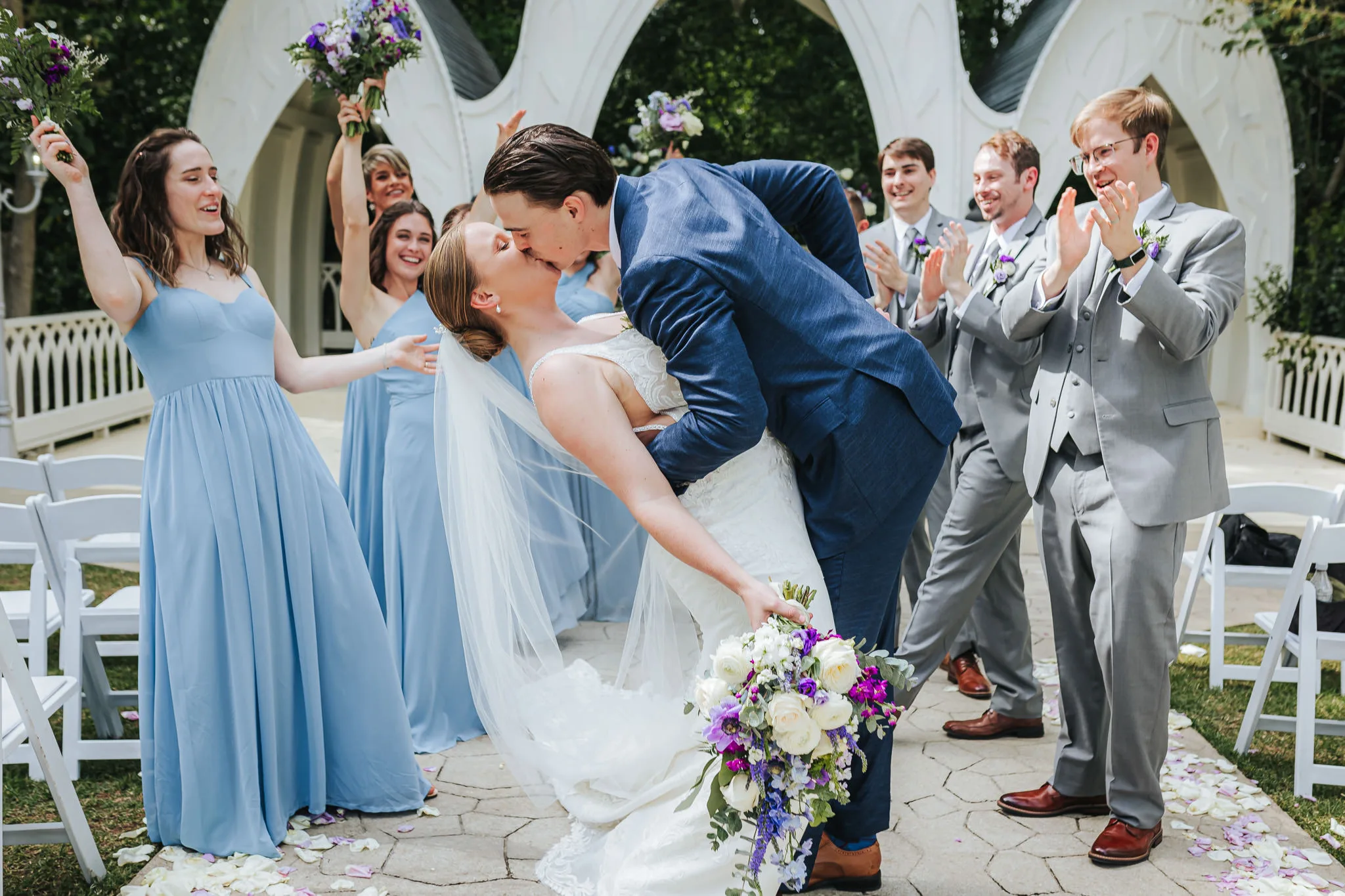 Wedding Formals: a dip kiss as the wedding party cheers, at their wedding at The Wildflower 301 in Greensboro, GA