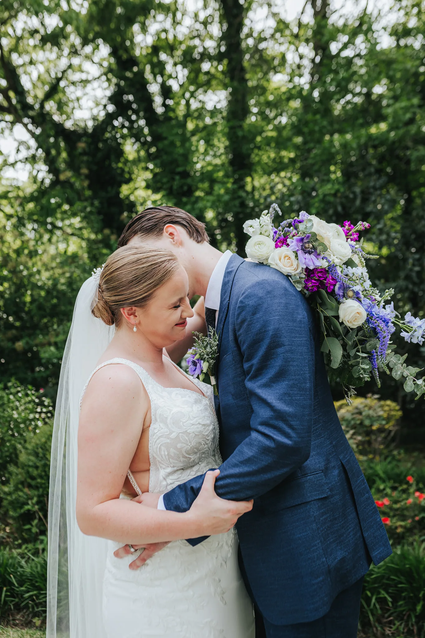 Wedding Formals: a hug with her bouquet over his shoulder, at their wedding at The Wildflower 301 in Greensboro, GA