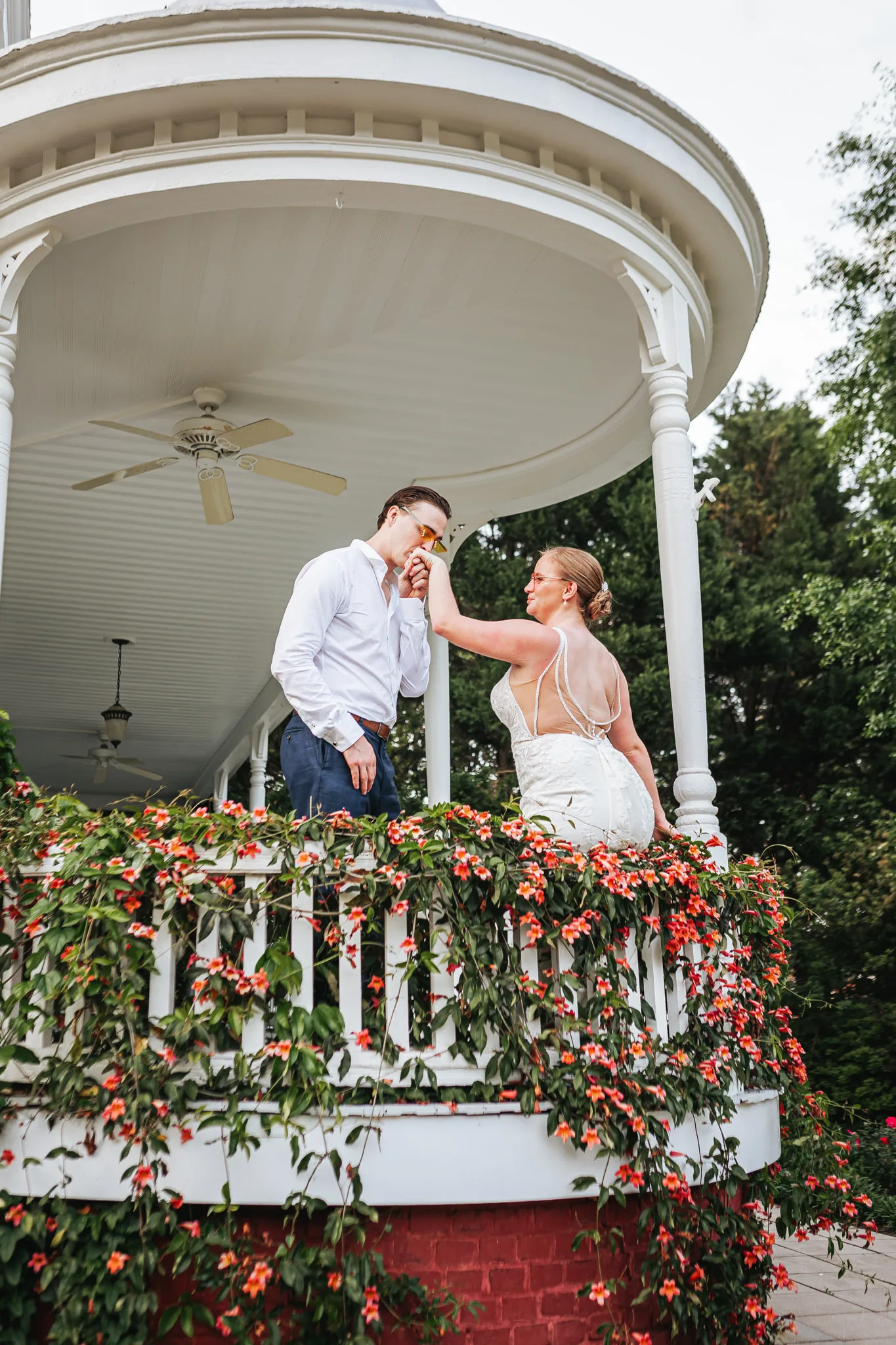 Wedding Formals: the groom kissing her hand on the gazebo covered in orange flowers, at their wedding at The Wildflower 301 in Greensboro, GA