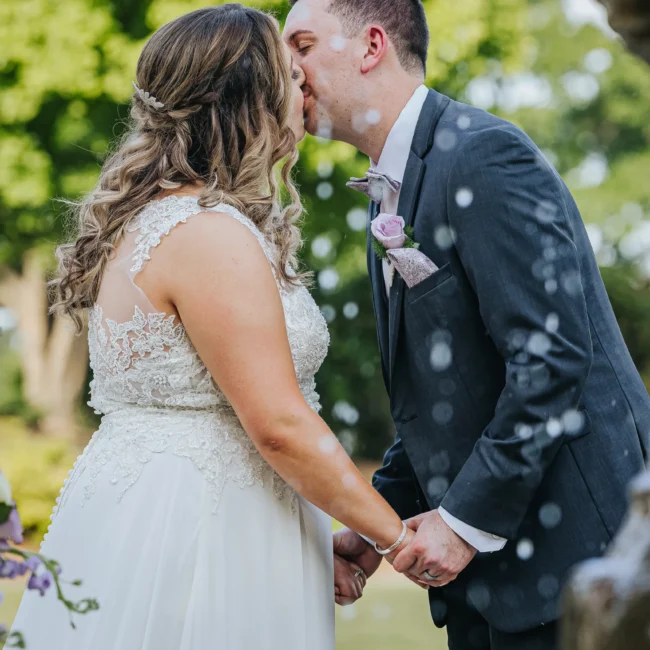 Wedding Ceremony: the first kiss with the fountain spraying behind them at their wedding at the Country Club of Roswell in Roswell, GA