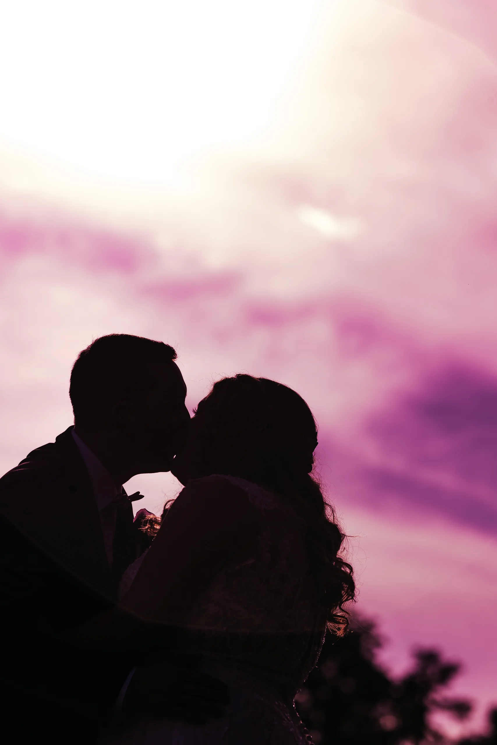 Wedding Formals: a kiss in silhouette against a pink sky at their wedding at the Country Club of Roswell in Roswell, GA
