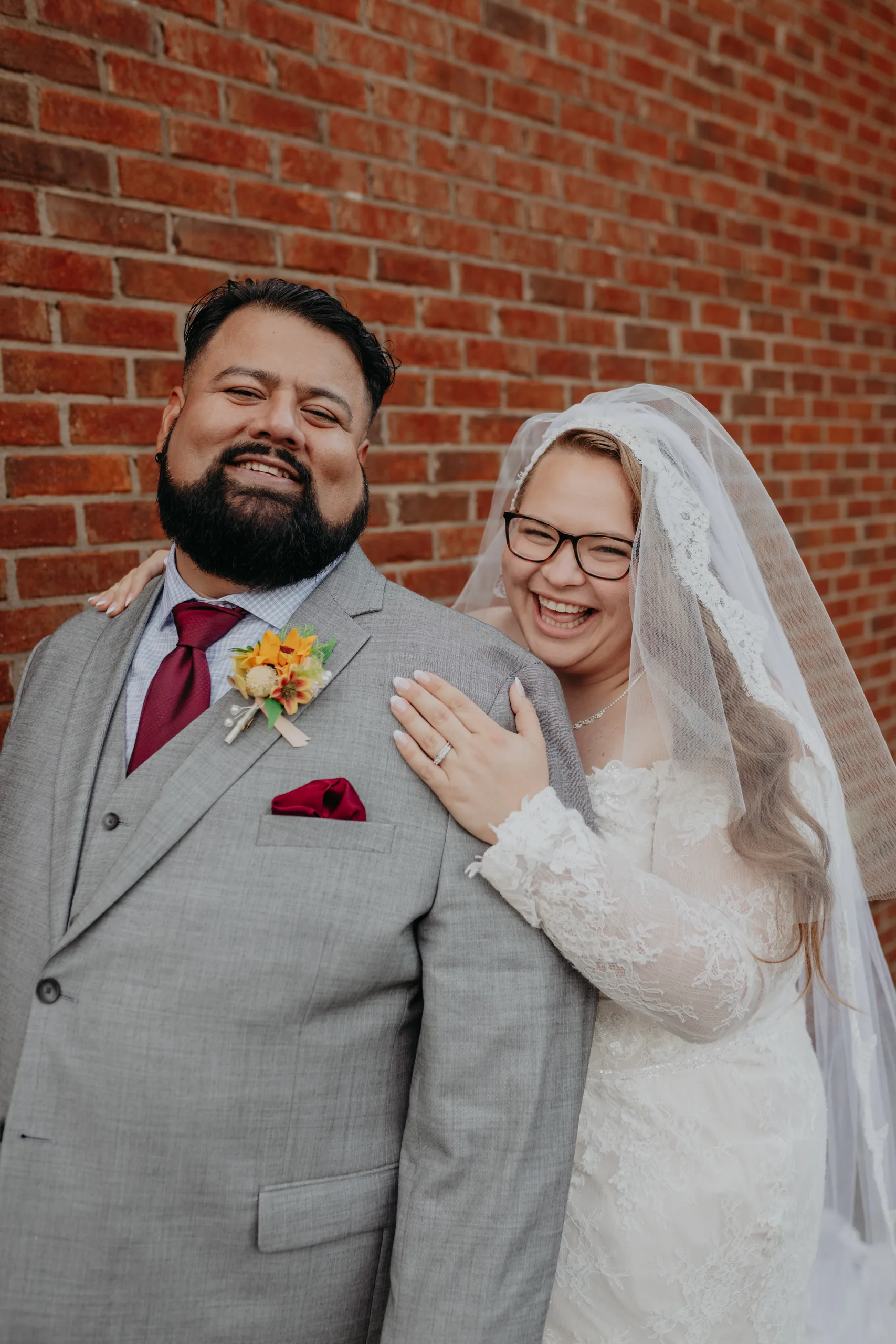 Wedding Formals: laughing together against the brick wall, at their wedding at 550 Trackside in Lawrenceville, GA