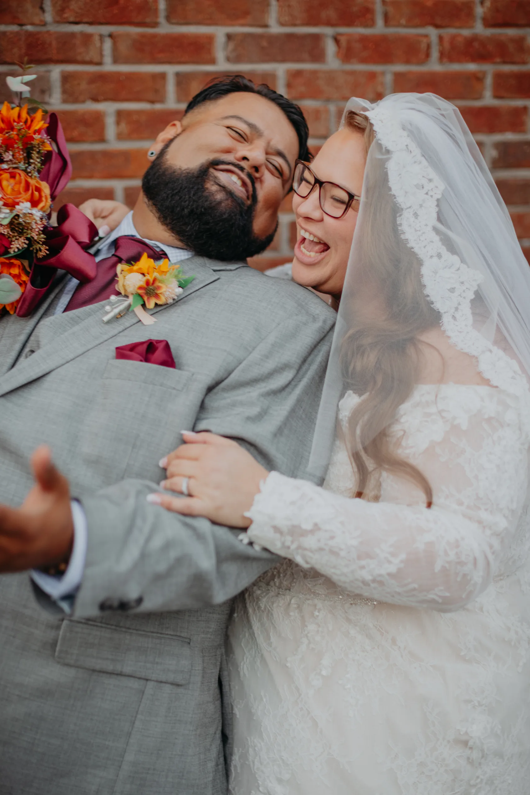 Wedding Formals: laughing together against the brick wall, at their wedding at 550 Trackside in Lawrenceville, GA