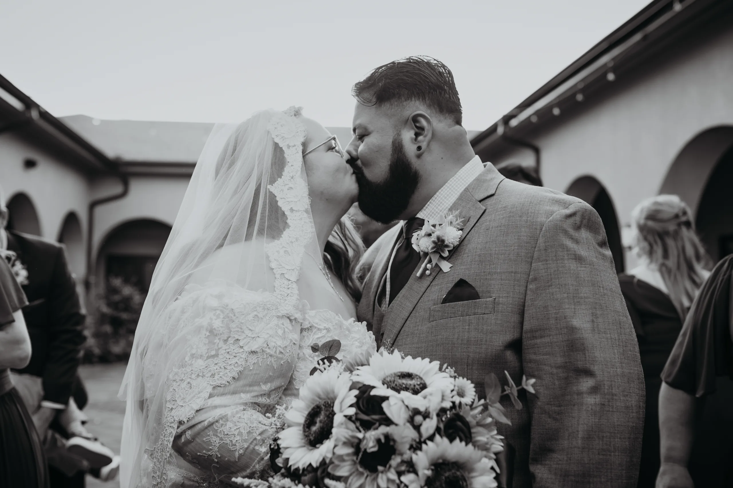 Wedding Formals: a kiss over her sunflower bouquet, in black and white, at their wedding at St. Lawrence Catholic Church in Lawrenceville, GA