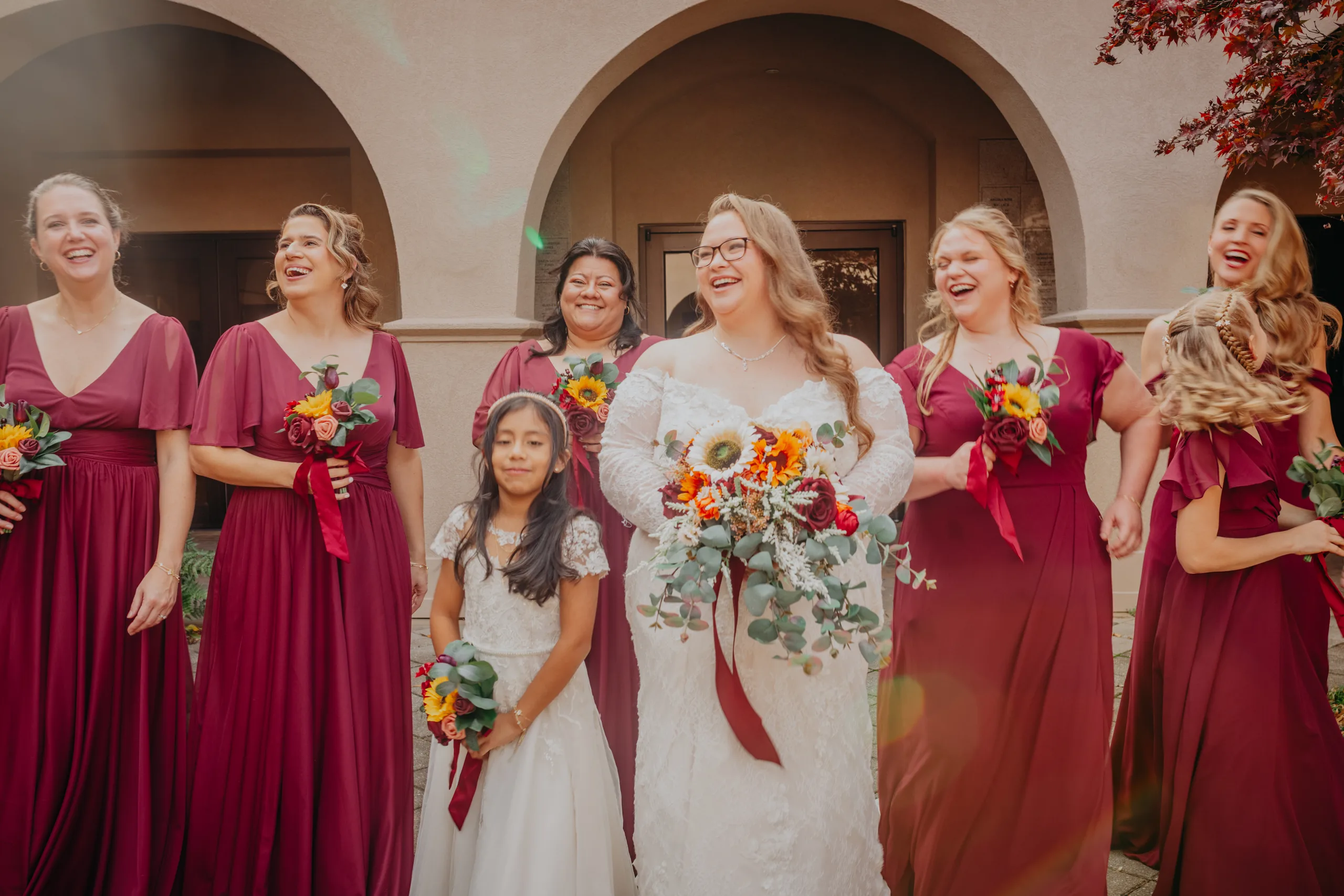Wedding Party: the bride with her bridesmaids in burgundy and the flower girl, at their wedding at St. Lawrence Catholic Church in Lawrenceville, GA