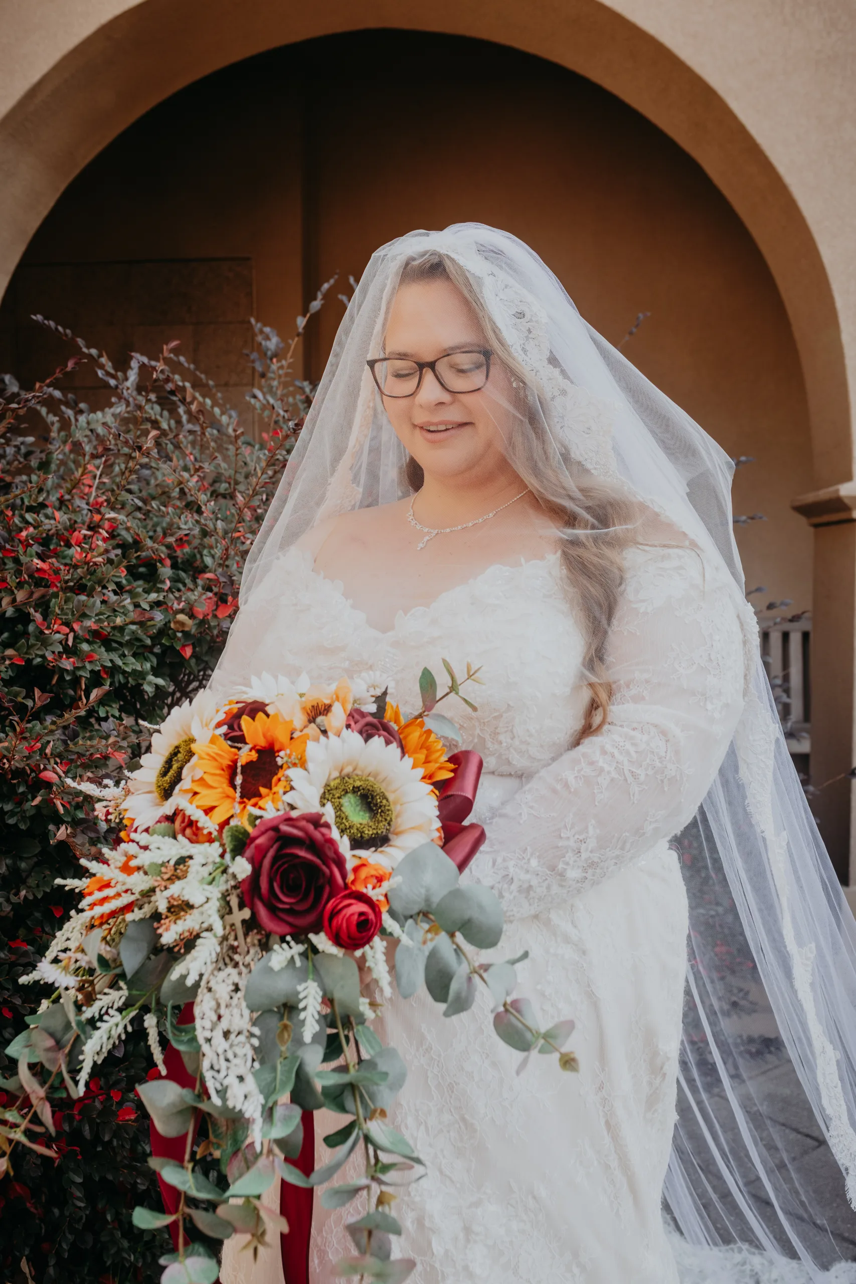Bridal Portraits: the bride with her sunflower bouquet under an arch, at their wedding at St. Lawrence Catholic Church in Lawrenceville, GA
