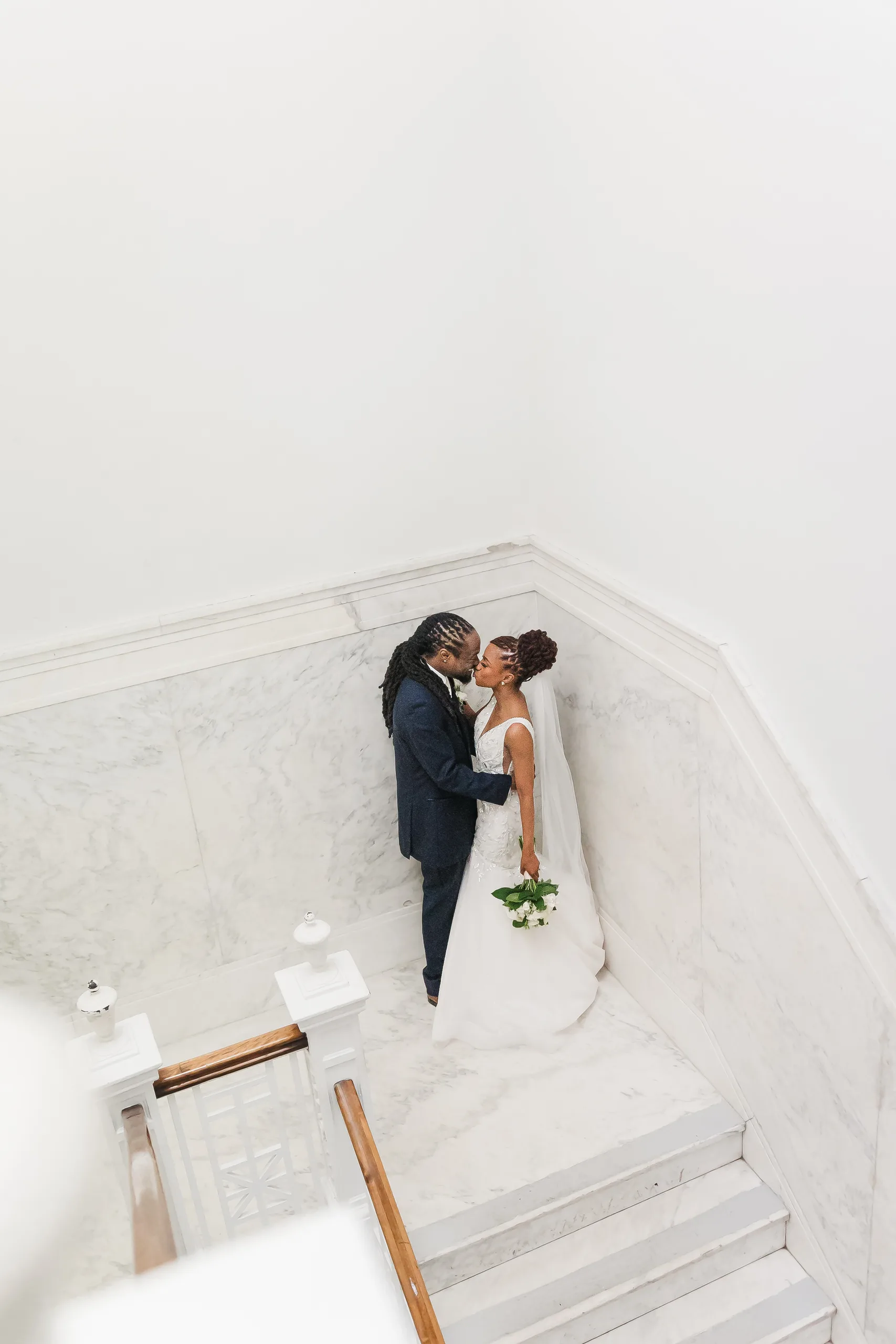 Wedding Formals: a kiss in the marble stairwell from above, at their wedding at the Historic DeKalb Courthouse in Decatur, GA