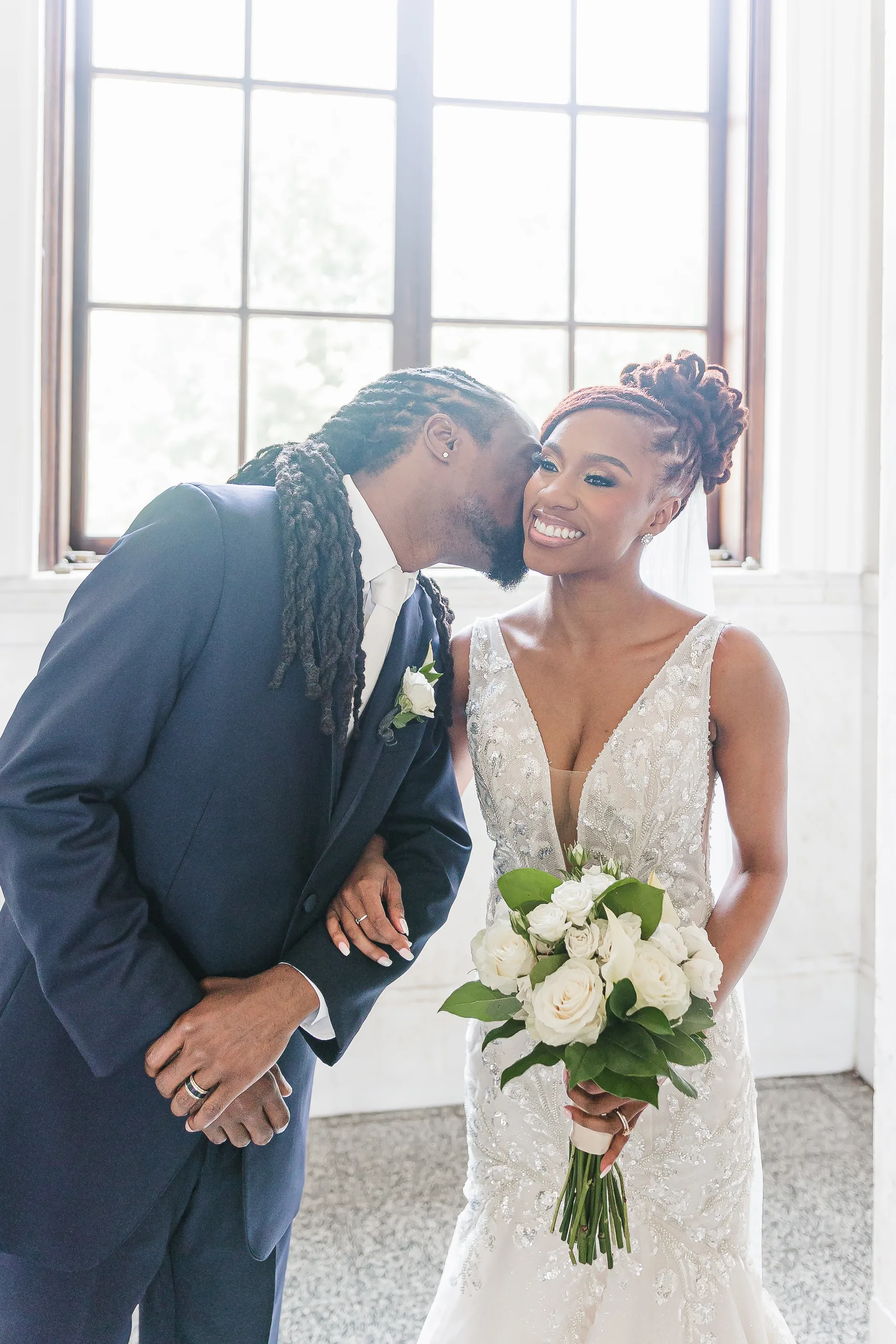 Wedding Formals: the groom kissing her cheek by the tall windows, at their wedding at the Historic DeKalb Courthouse in Decatur, GA