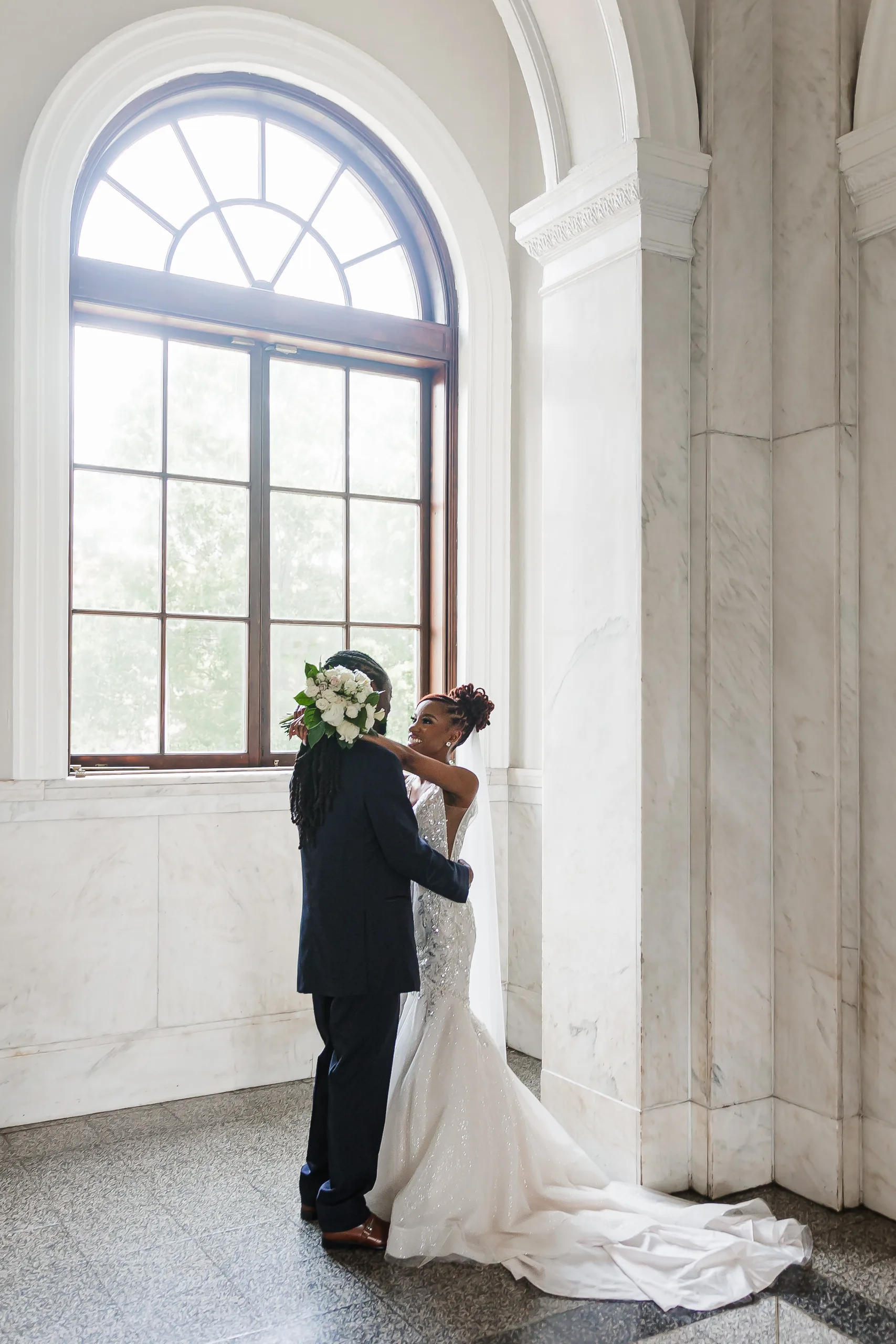 Wedding Formals: an embrace under the arched window, at their wedding at the Historic DeKalb Courthouse in Decatur, GA