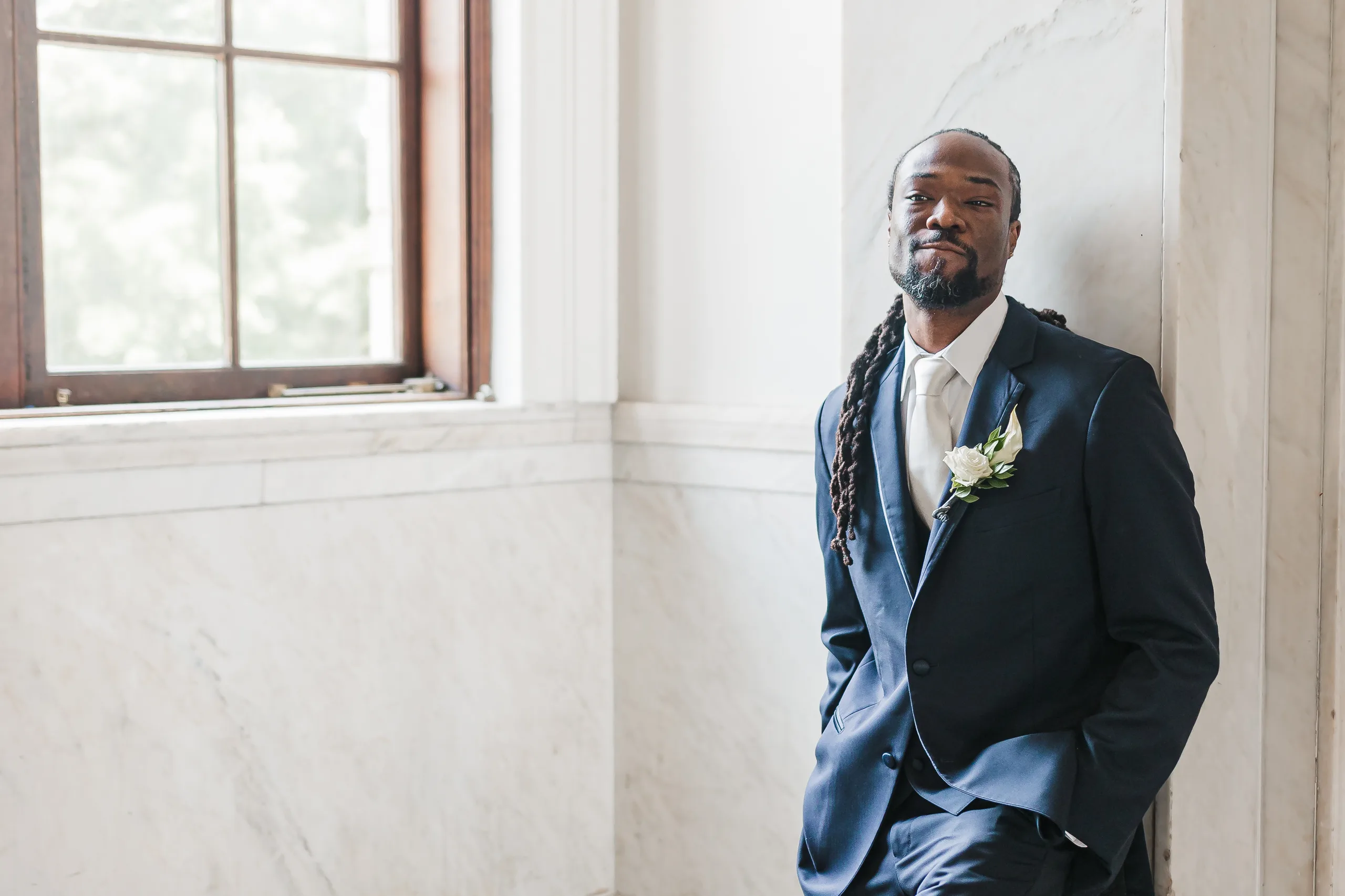 Wedding Formals: the groom leaning on the marble wall, at their wedding at the Historic DeKalb Courthouse in Decatur, GA