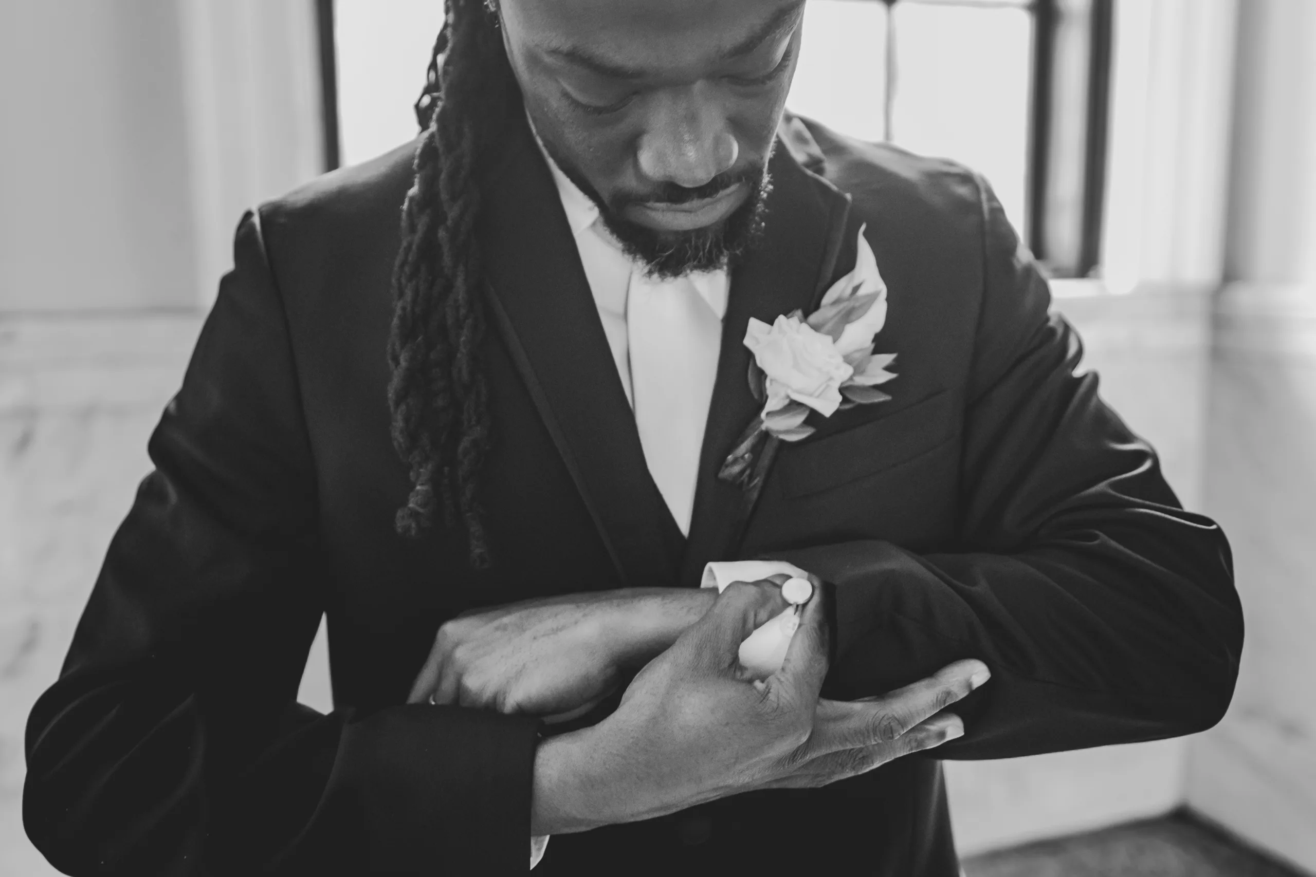 Wedding Formals: the groom fixing his cuff, in black and white, at their wedding at the Historic DeKalb Courthouse in Decatur, GA