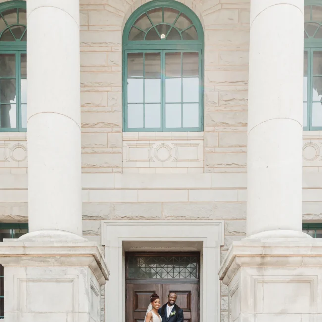 Wedding Formals: the two of them at the front doors between the columns, at their wedding at the Historic DeKalb Courthouse in Decatur, GA