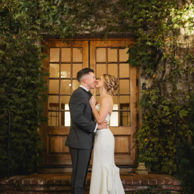 Wedding Formals: the two of them kissing on the brick steps under the ivy-covered doorway, at their wedding at Summerour Studio in Atlanta, GA
