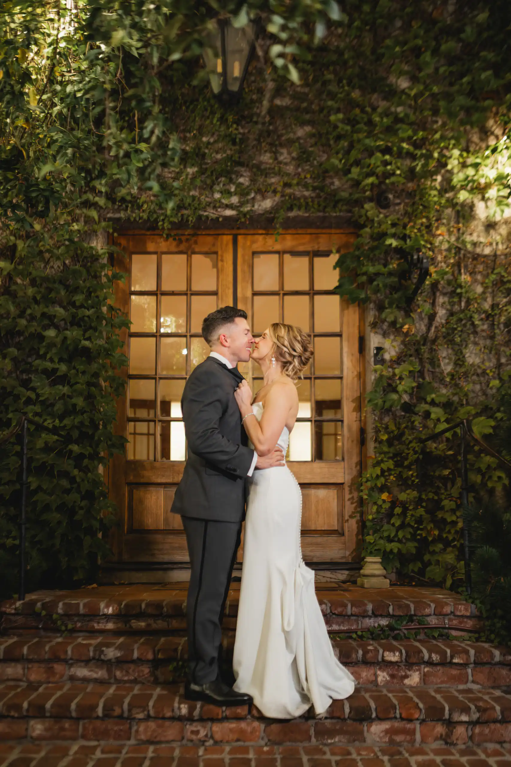 Wedding Formals: the two of them kissing on the brick steps under the ivy-covered doorway, at their wedding at Summerour Studio in Atlanta, GA