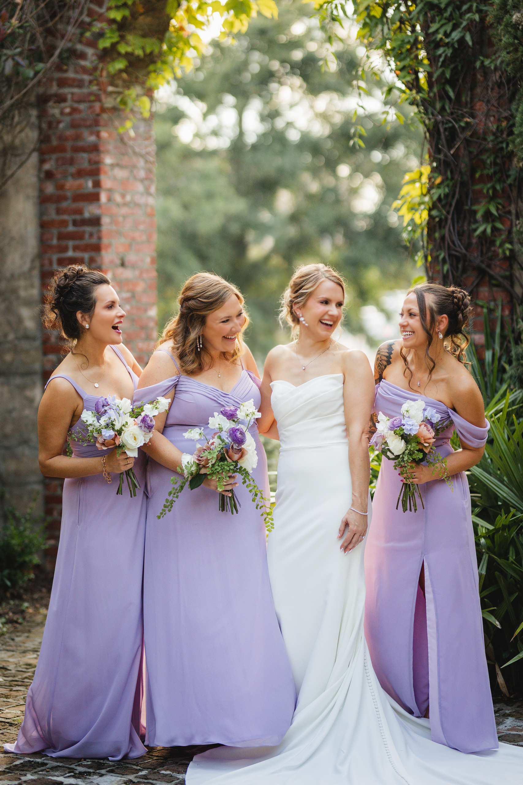 Wedding Party: her bridesmaids in lavender laughing with her, at their wedding at Summerour Studio in Atlanta, GA