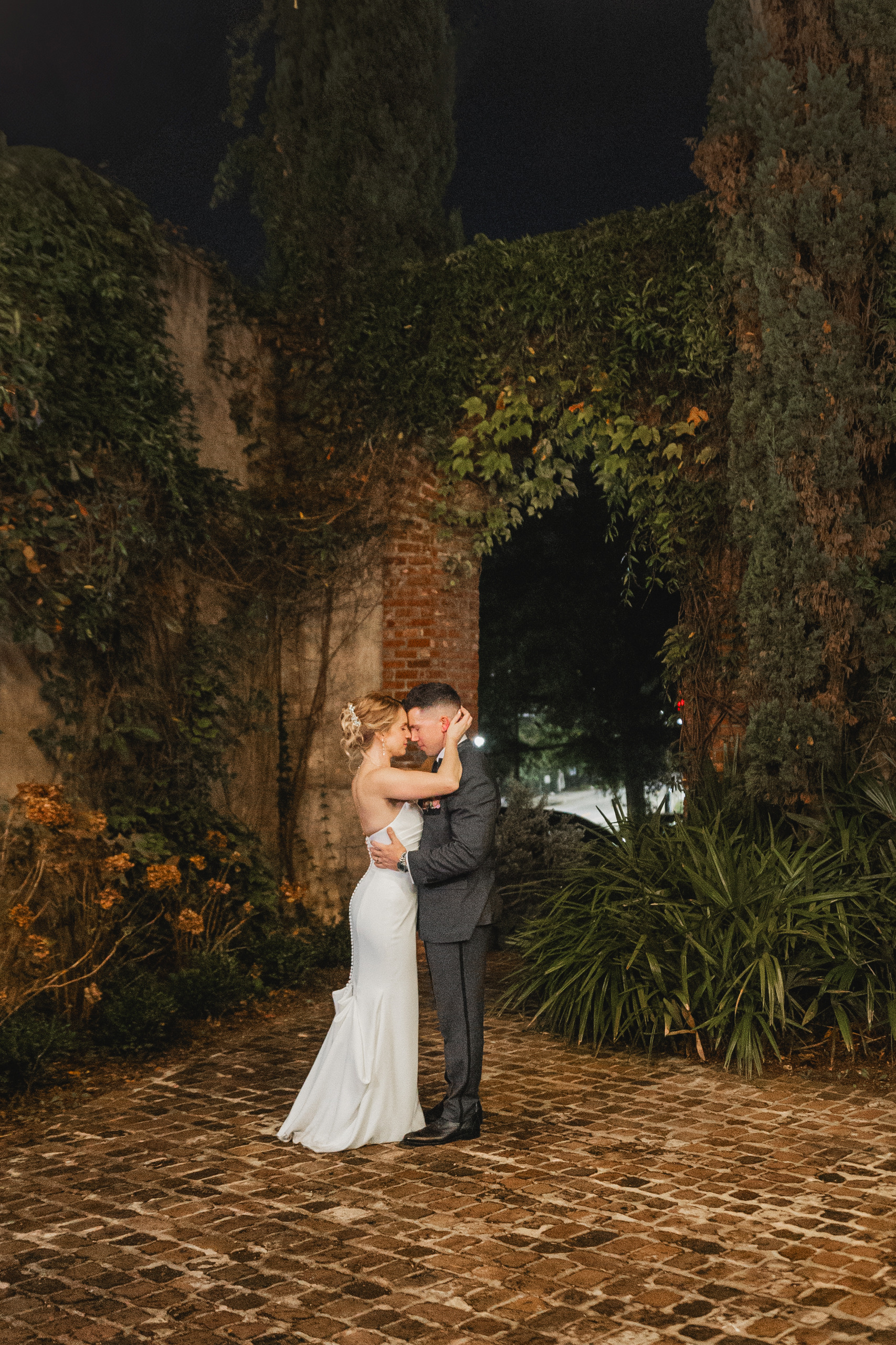 Wedding Formals: the two of them close together on the brick courtyard after dark, at their wedding at Summerour Studio in Atlanta, GA