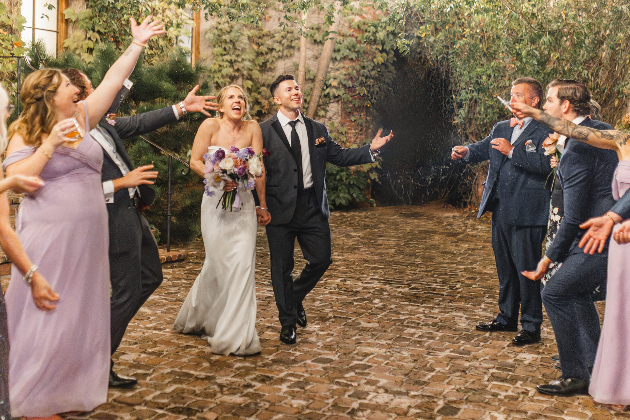 Recessional: walking out through a spray of champagne on the brick courtyard, at their wedding at Summerour Studio in Atlanta, GA