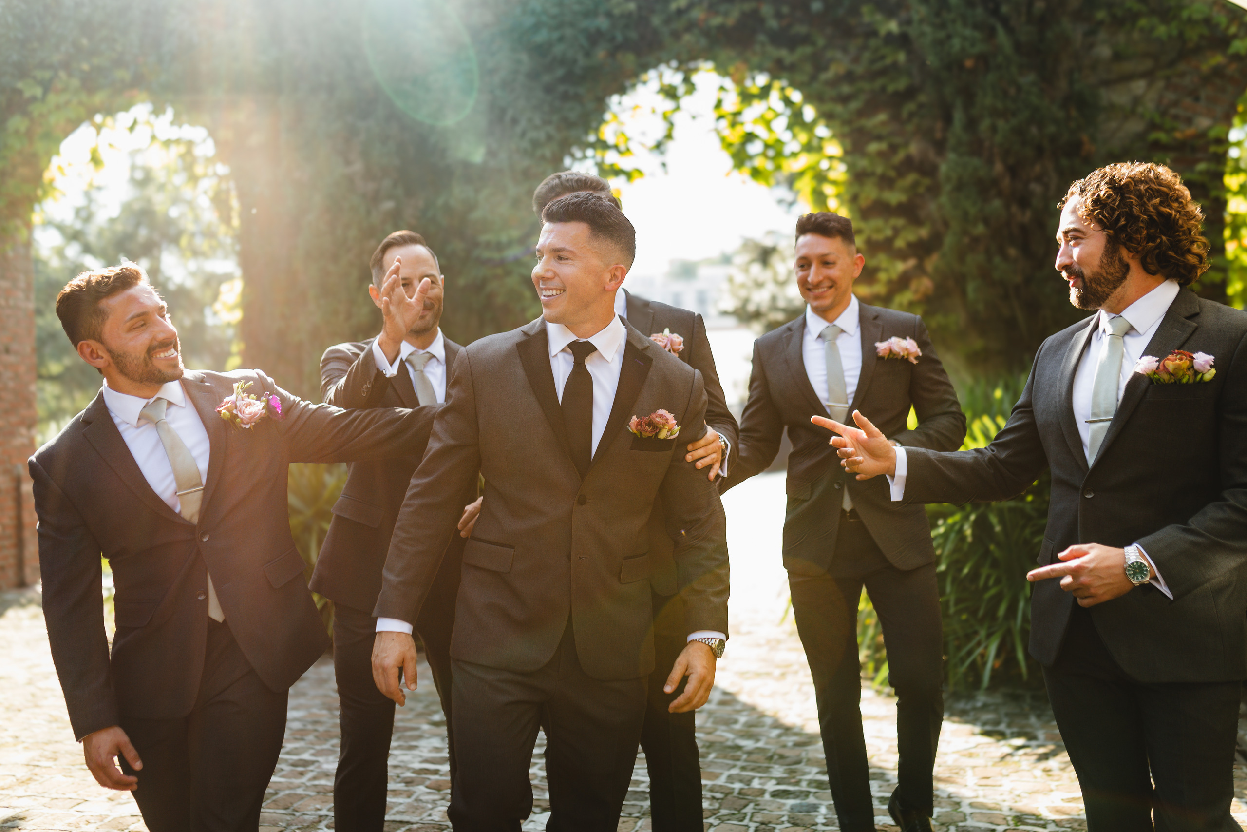 Wedding Party: his groomsmen walking the ivy archway in the last of the sun, at their wedding at Summerour Studio in Atlanta, GA