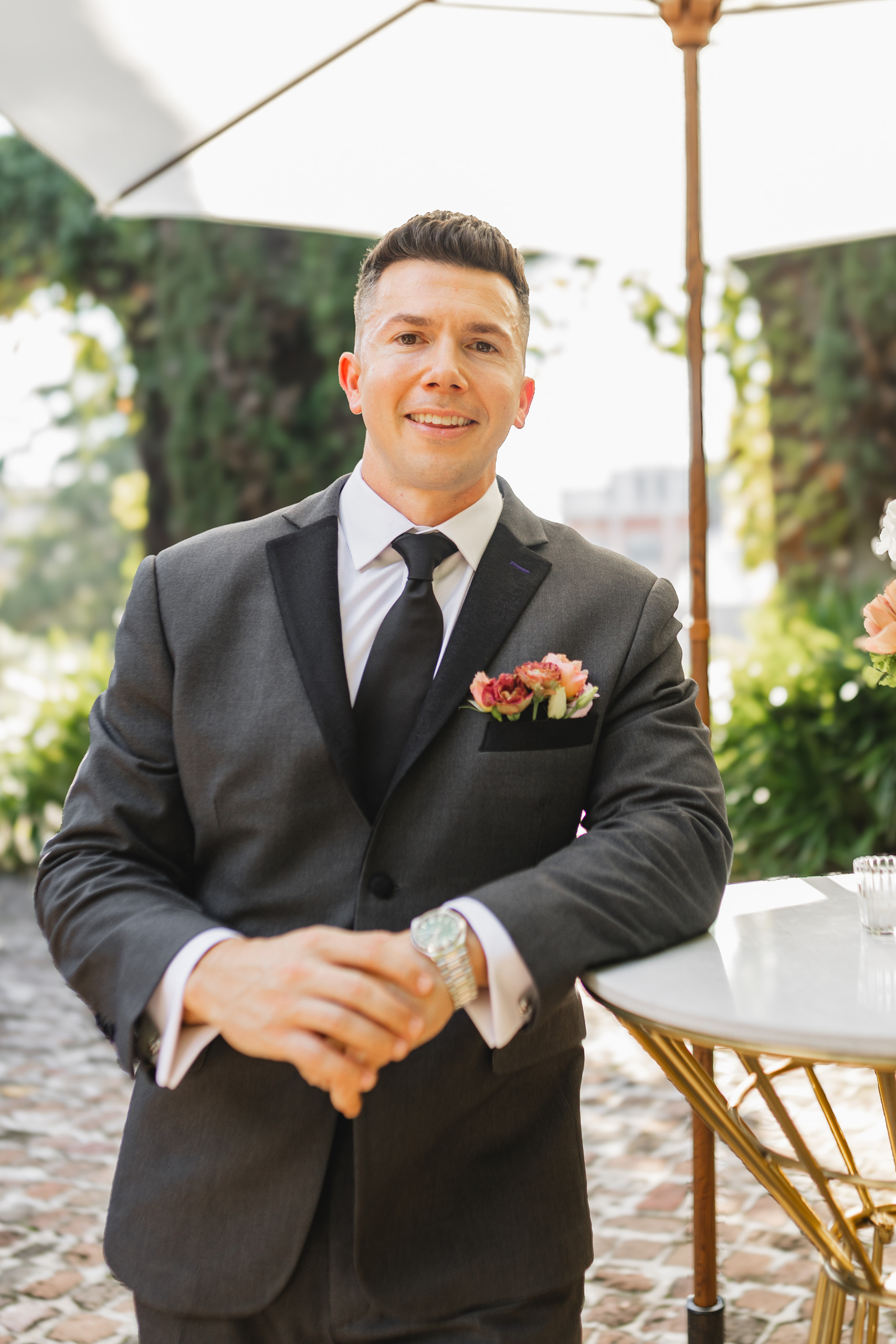 Groom Portraits: the groom on the courtyard under the umbrella, at their wedding at Summerour Studio in Atlanta, GA