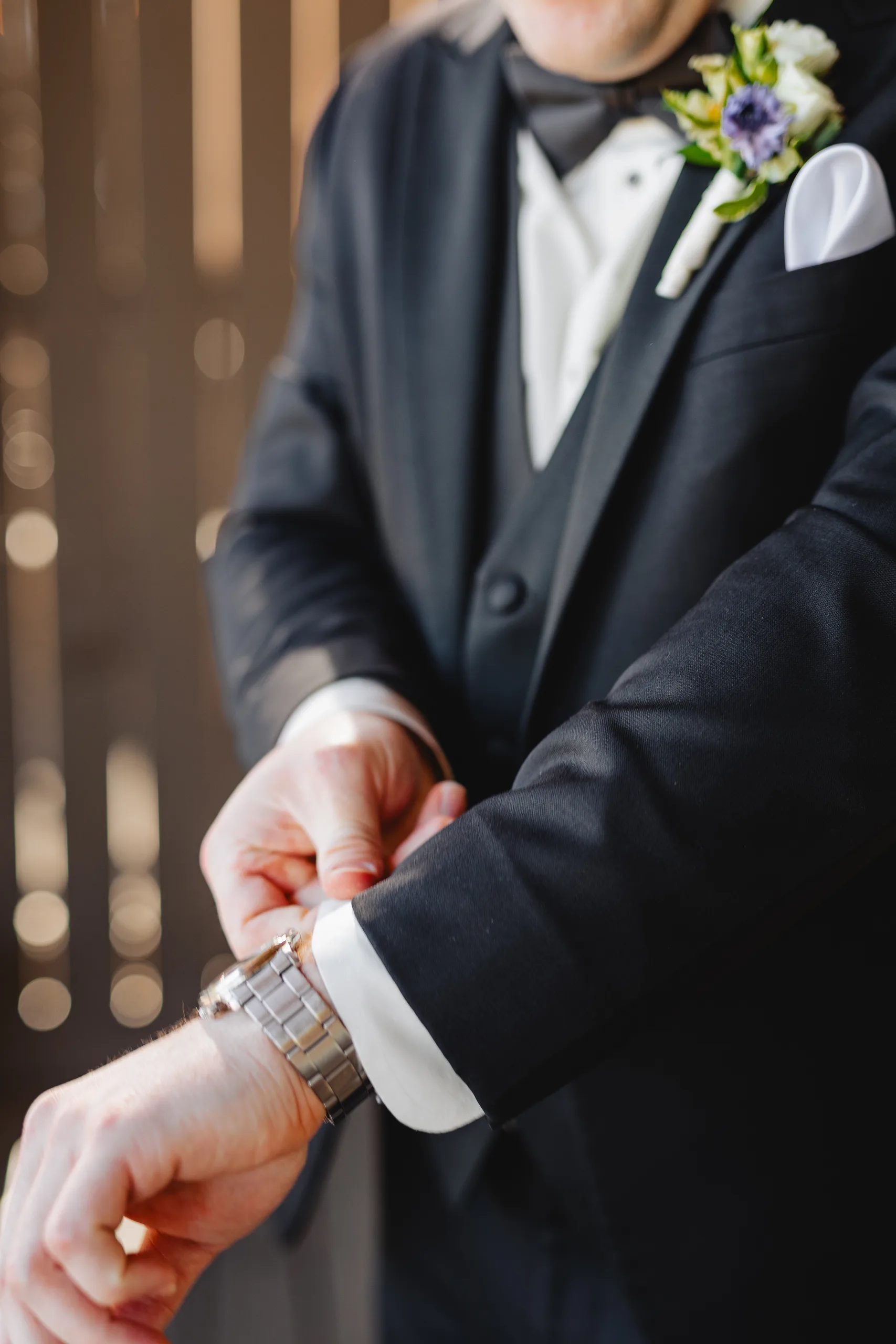 Getting Ready: the groom fastening his watch before their wedding at Ivy Hall at Roswell Mill in Roswell, GA