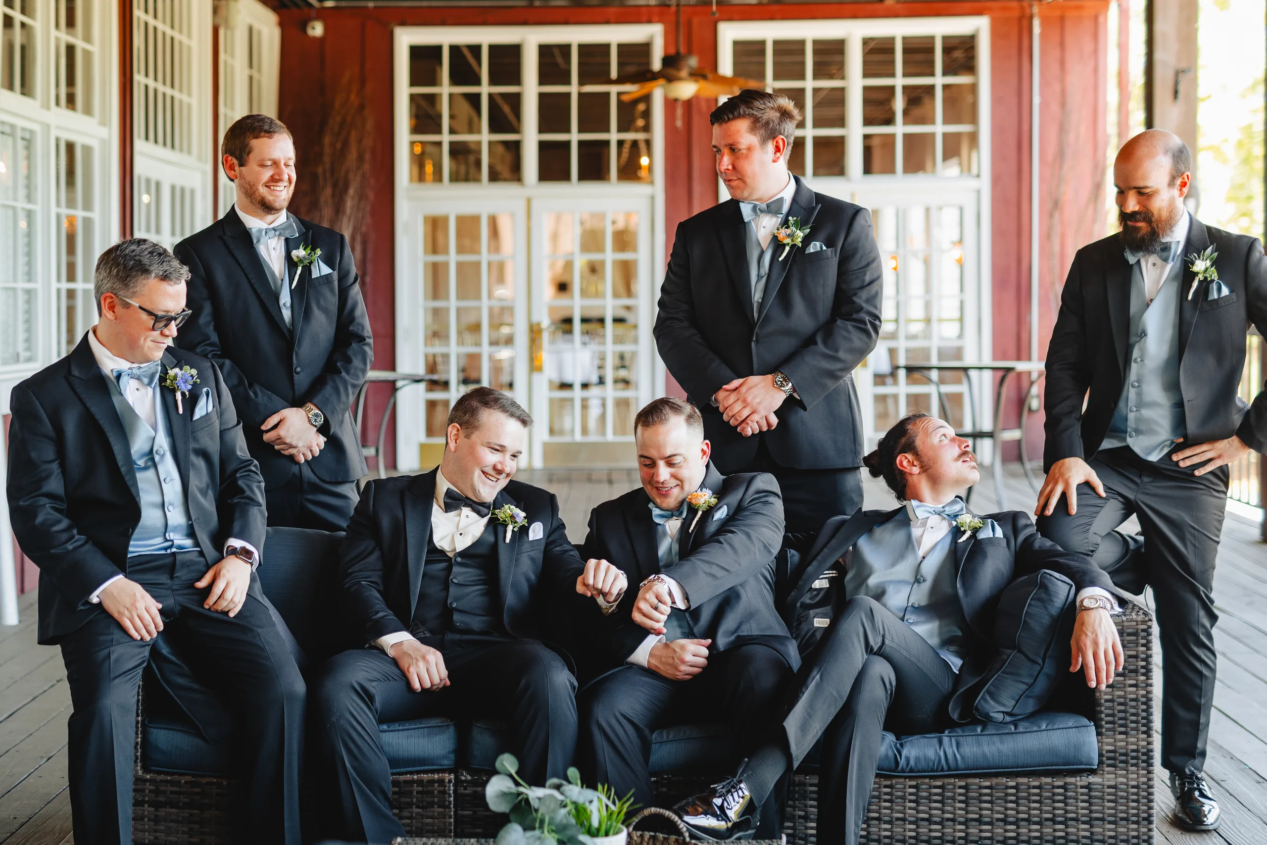 Wedding Party: the groomsmen lounging on the porch at their wedding at Ivy Hall at Roswell Mill in Roswell, GA
