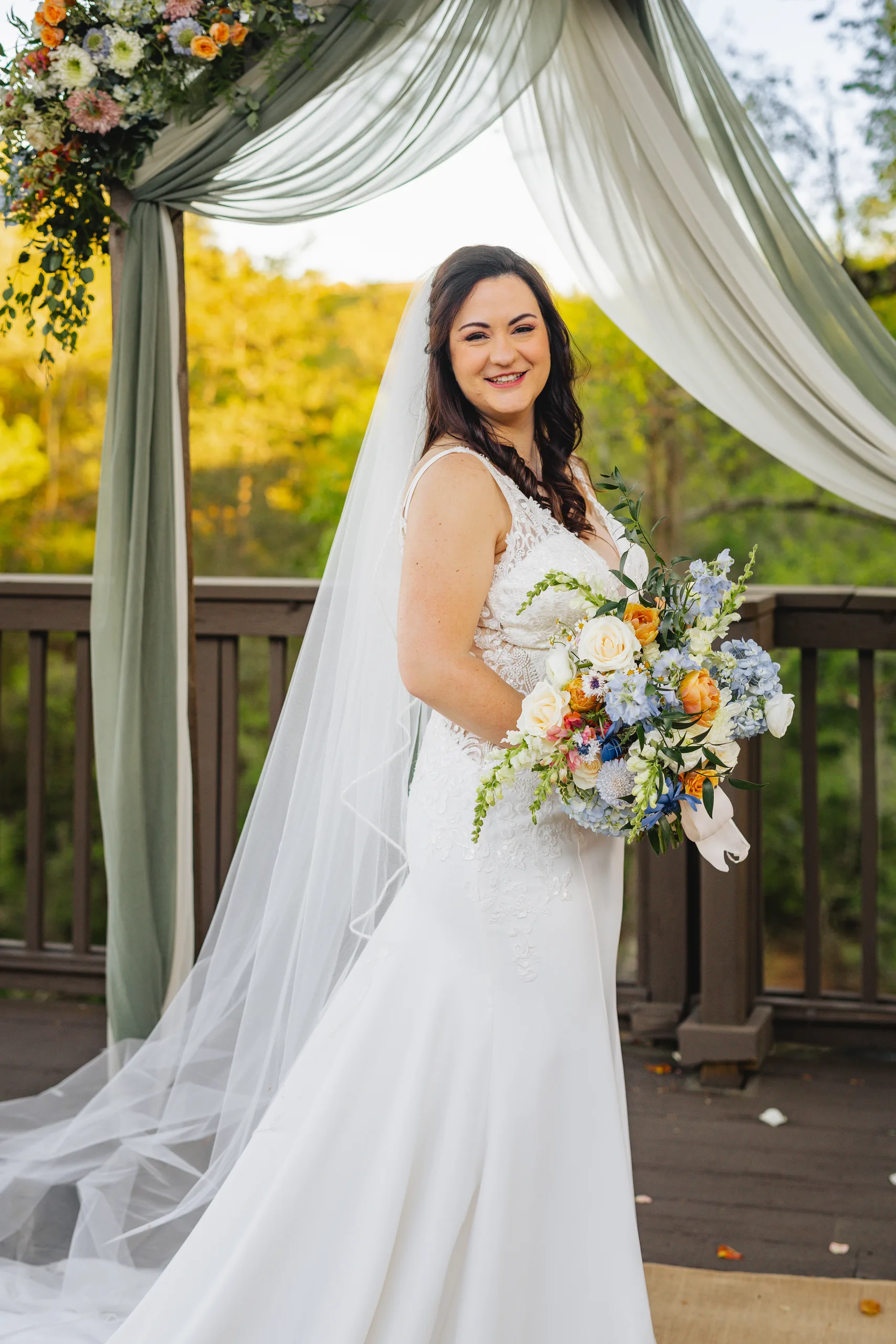 Bridal Portraits: the bride with her bouquet at the ceremony arch at their wedding at Ivy Hall at Roswell Mill in Roswell, GA