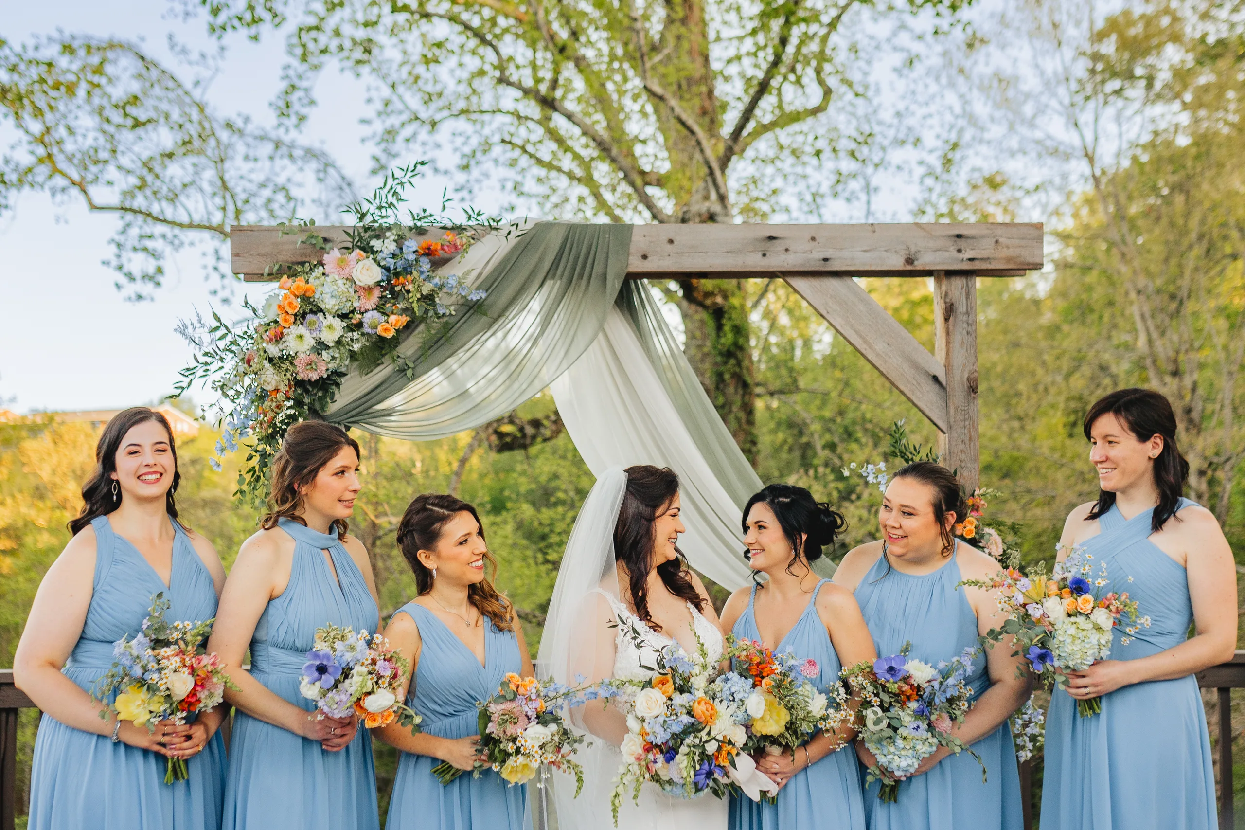 Wedding Party: the bride with her bridesmaids at the arch at their wedding at Ivy Hall at Roswell Mill in Roswell, GA
