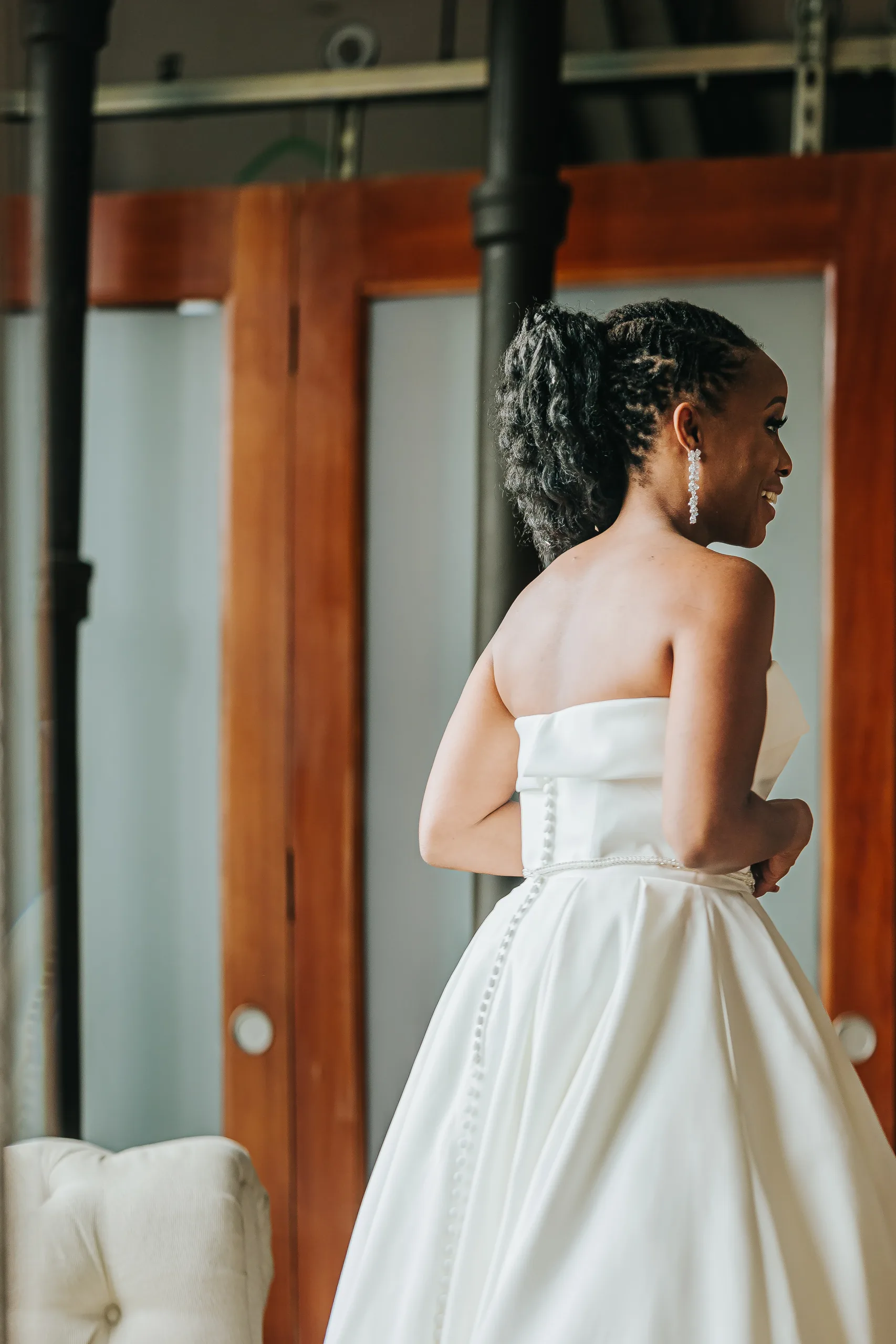 Bridal Portraits: the bride looking over her shoulder, the buttons down her back, at their wedding at Terminus 330 in Atlanta, GA
